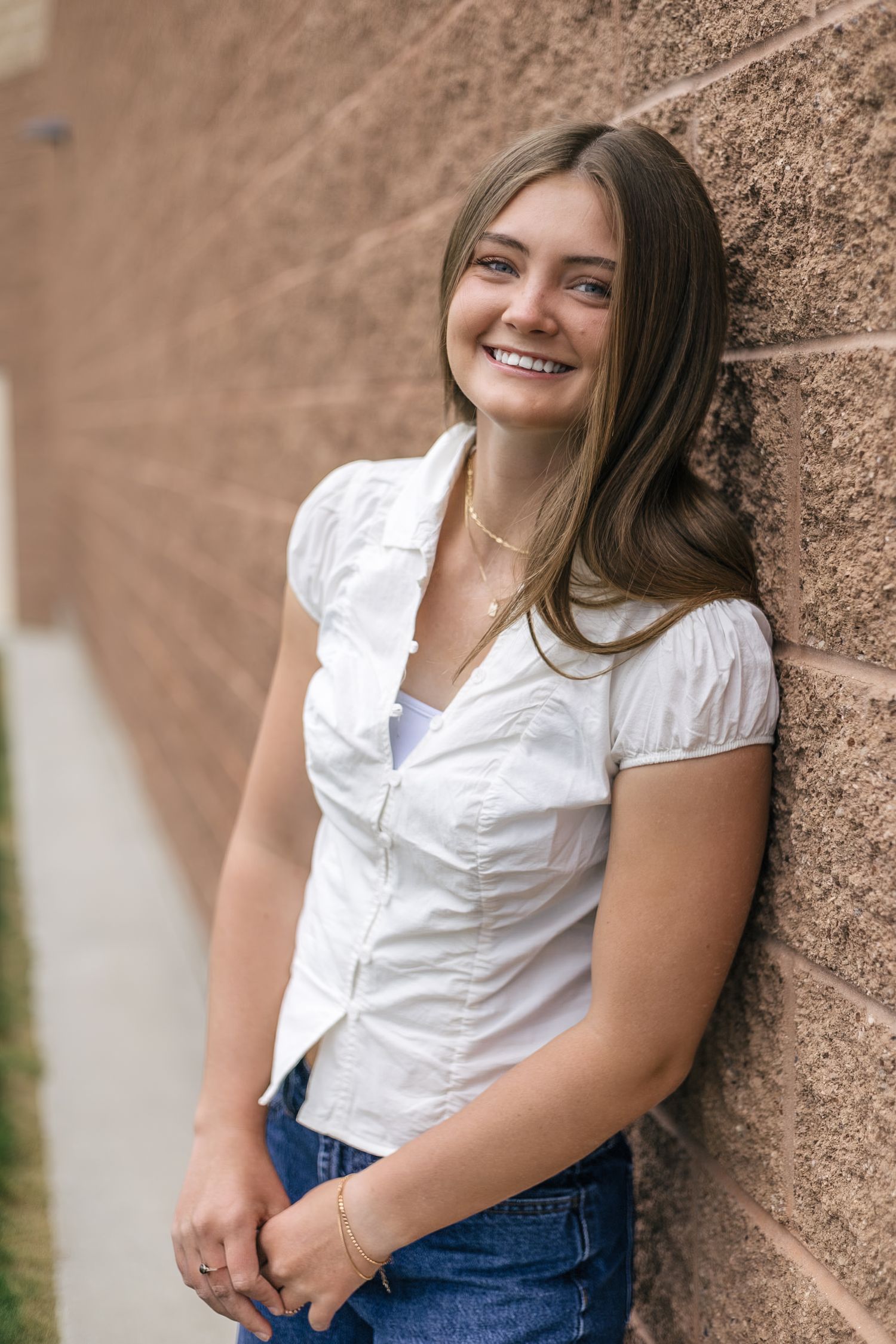 senior girl posing at her school, leaning against the wall