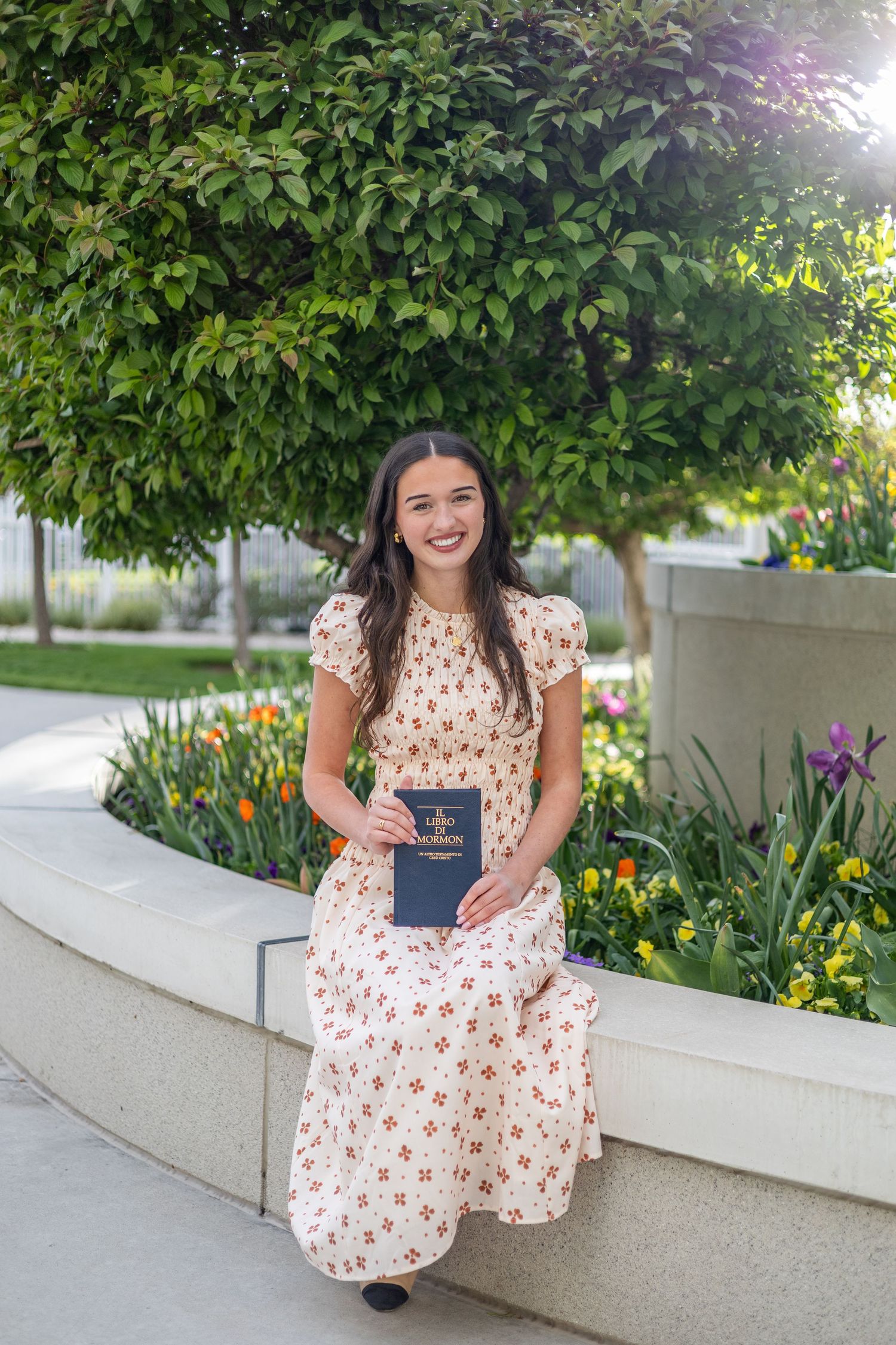 girl holding a book of scripture, sitting at an LDS temple