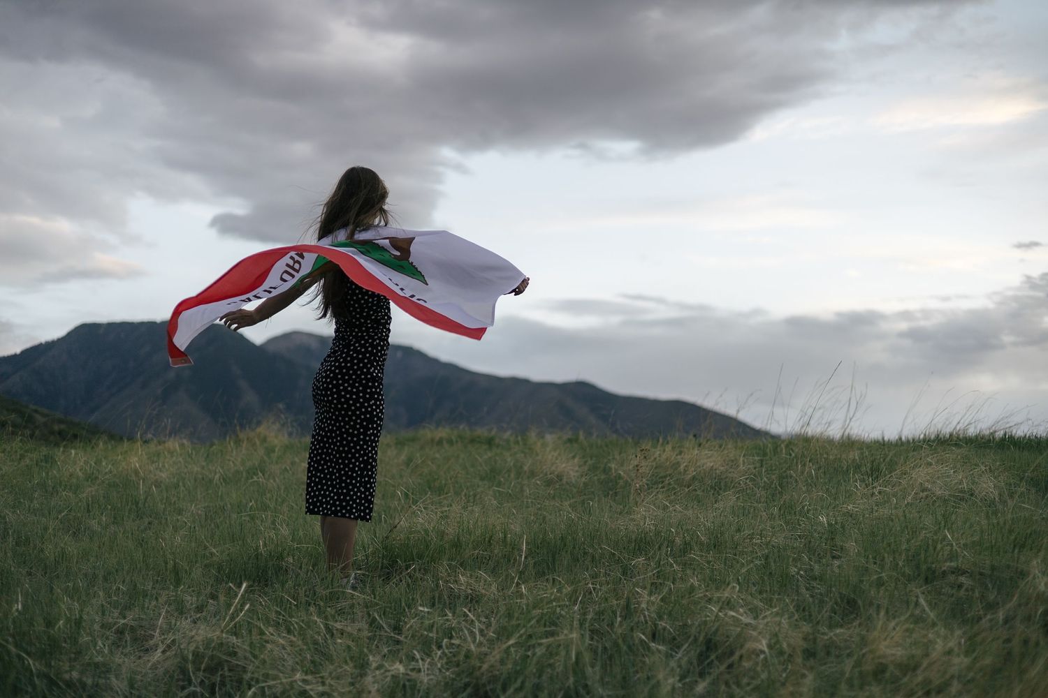 senior girl posing in a field, with california flag blowing in the wind