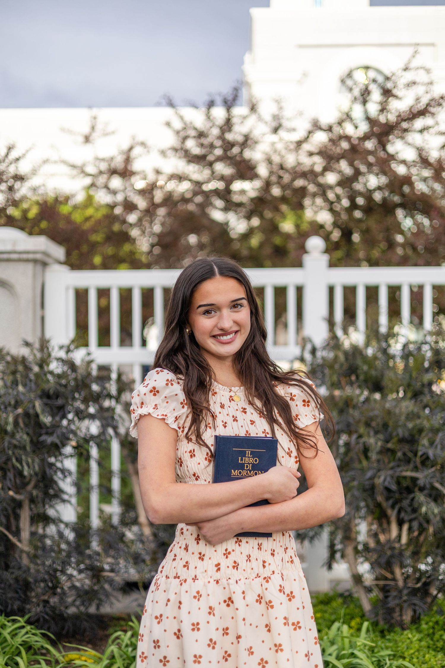 girl holding a book of scripture, posing in front of an LDS temple