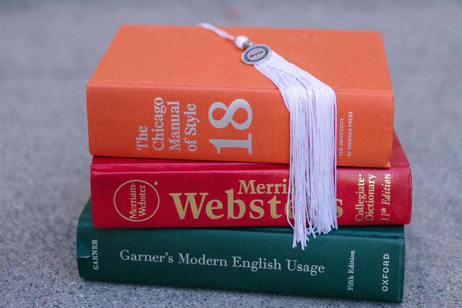 stack of resource books with BYU graduation tassel draped across the top