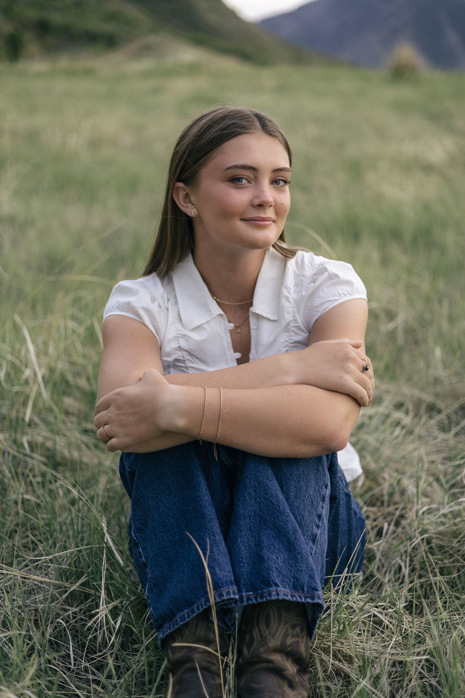 senior girl posing in a field, with hair tucked behind ears