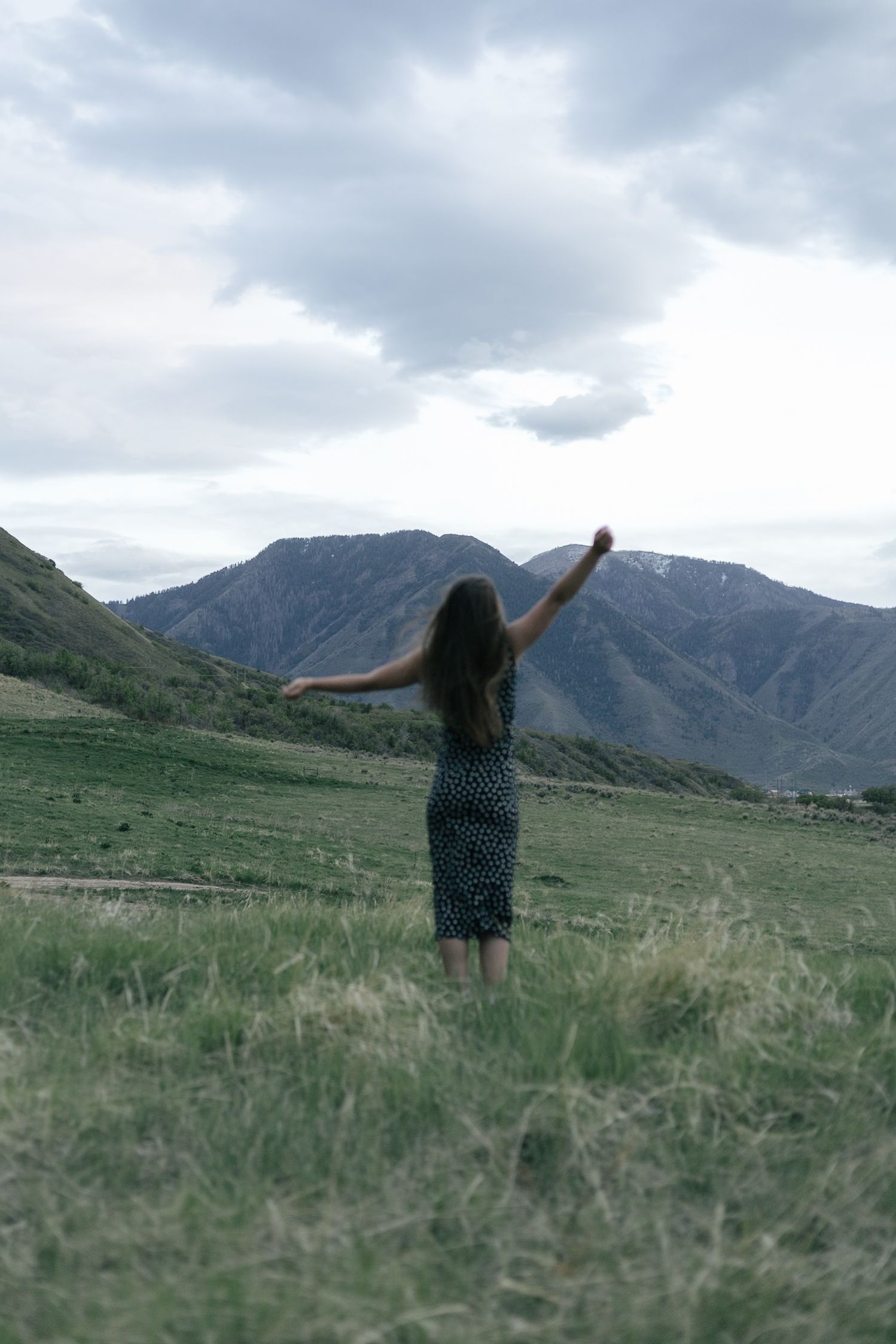 senior girl posing in a field, with arms outstretched