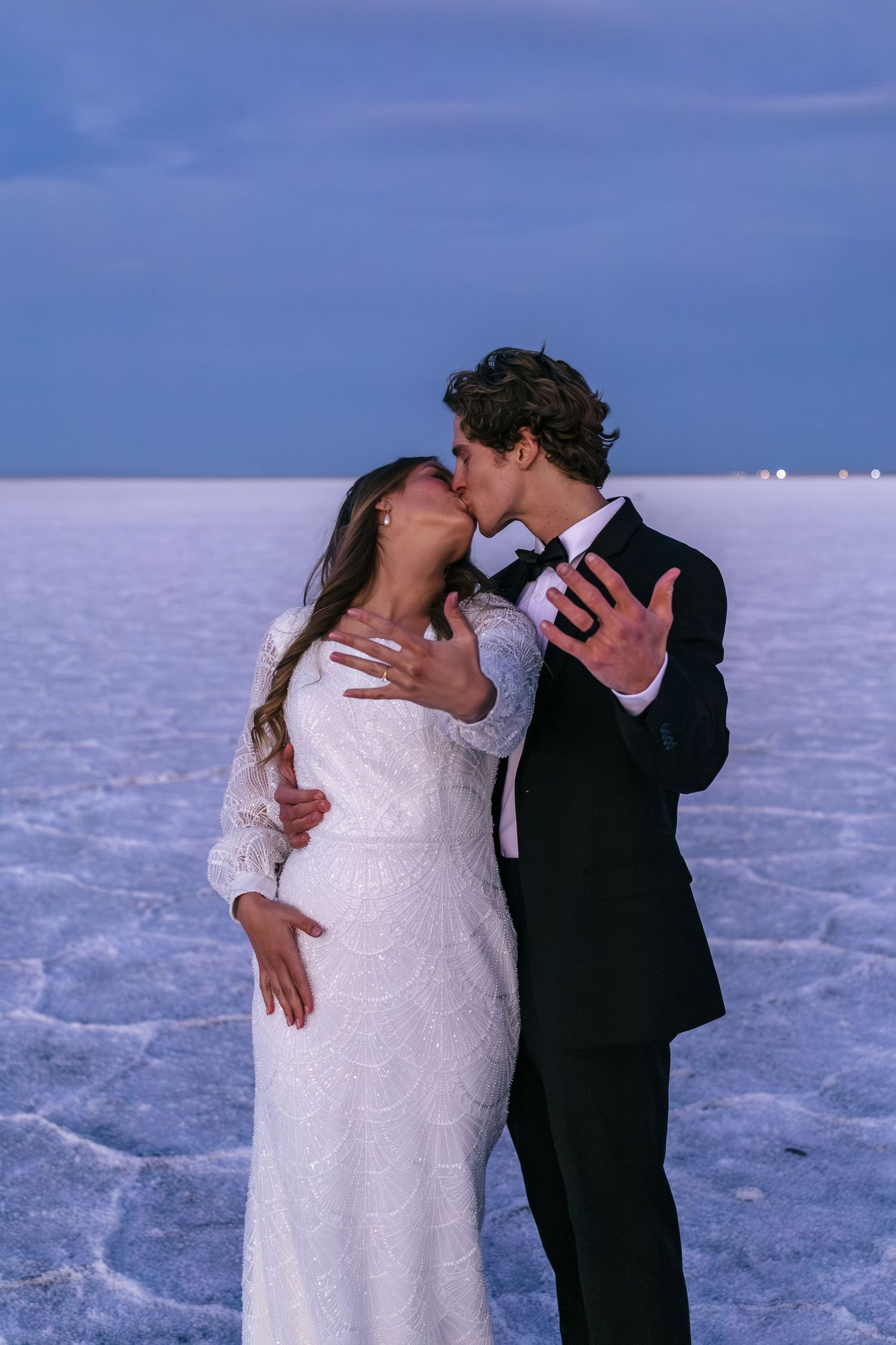 couple showing off their wedding bands on the Utah salt flats at sunset