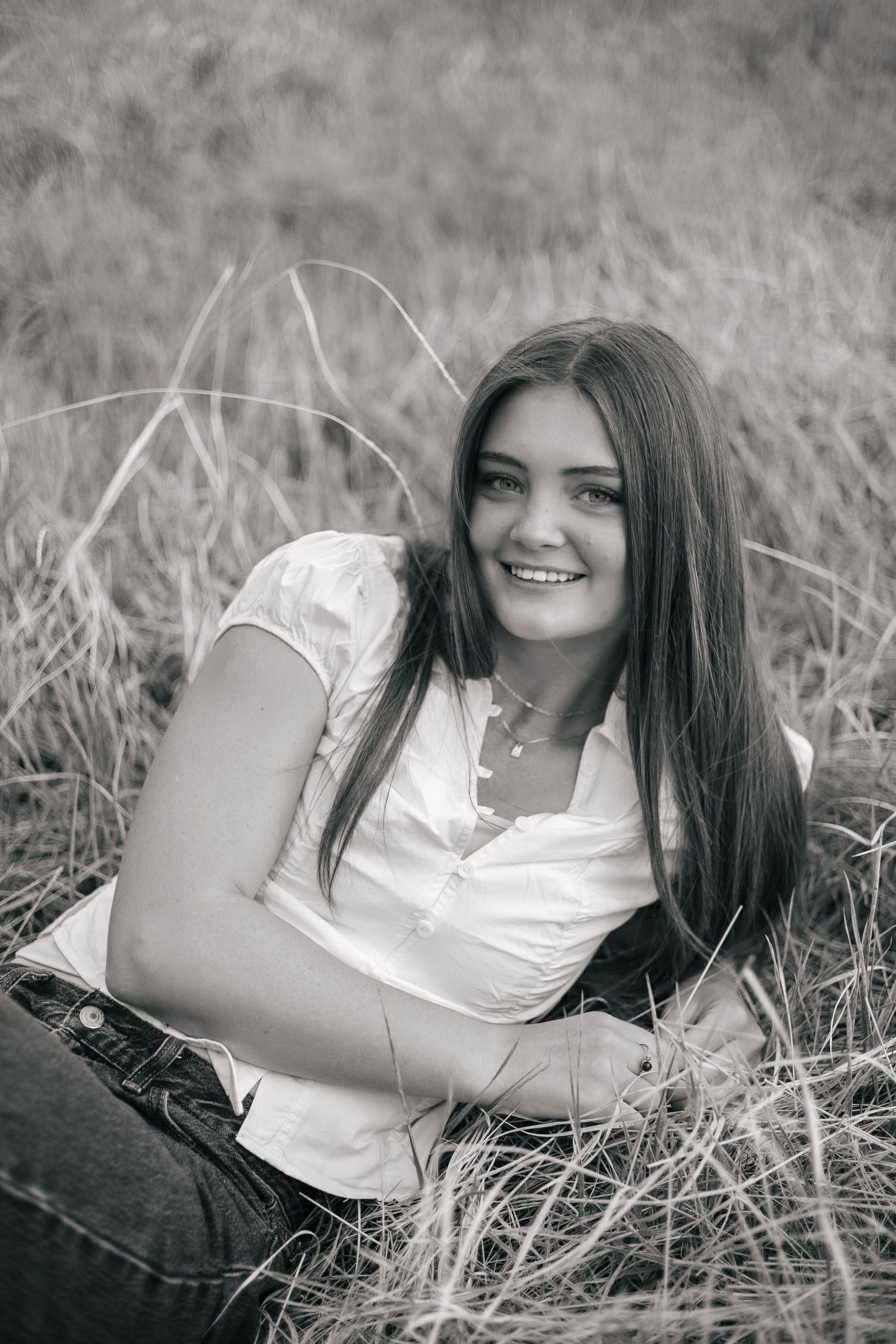 senior girl posing in a field, resting on elbow