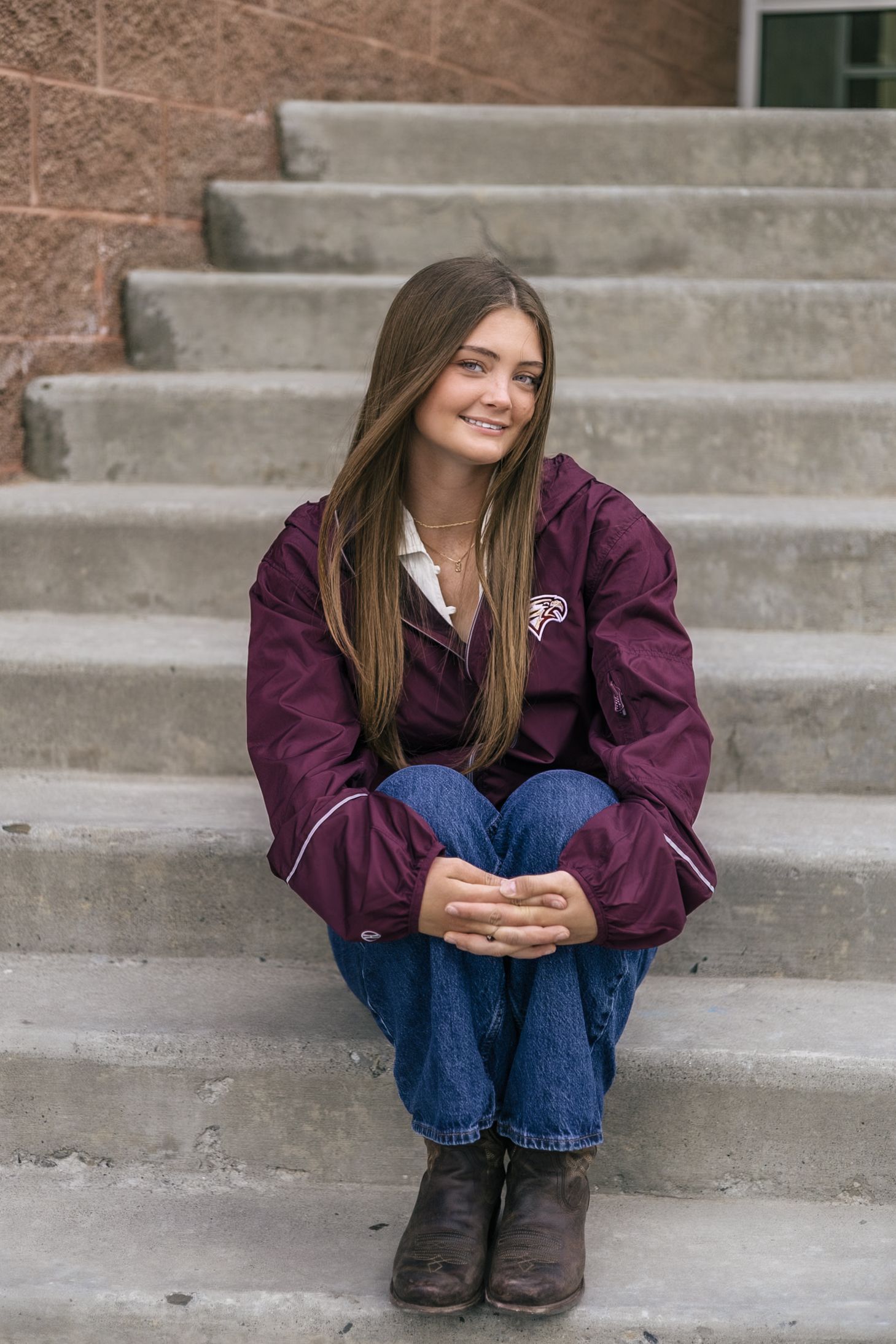 senior girl posing at her school, sitting on the stairs