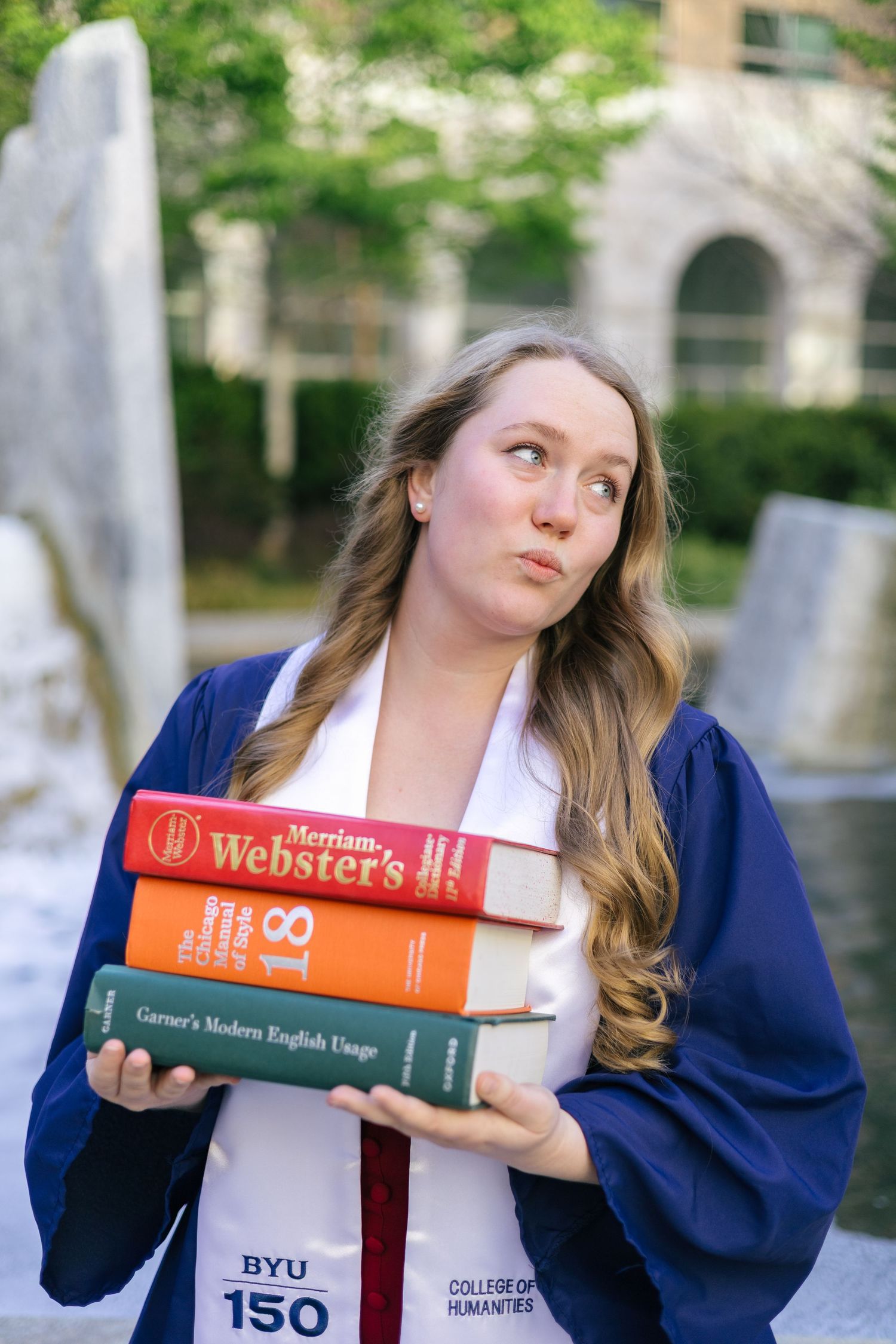 byu graduate posing with stack of resource books
