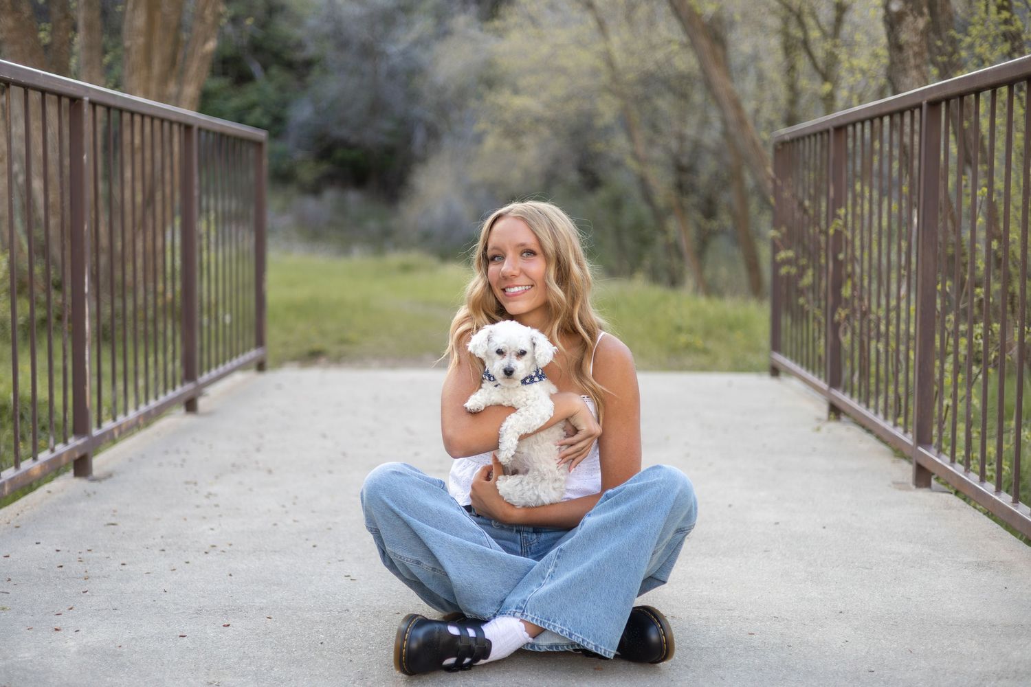senior girl with her dog on a bridge at a park for senior picture session