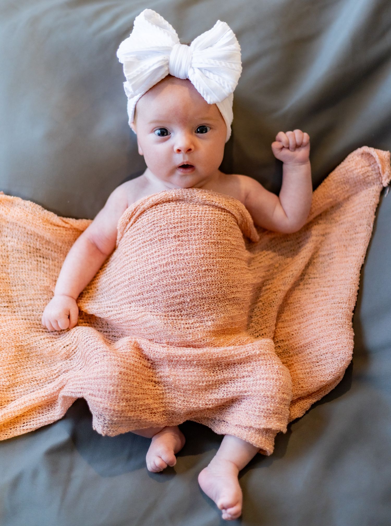 Baby wearing white bow headband lies on peach knit blanket in series of connected photos showing different angles. Cincinnati/ Northern Ky