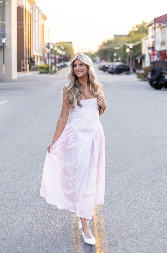 A person in a flowing light pink sundress poses on a small town street at sunset. Cincinnati/ northern Kentucky