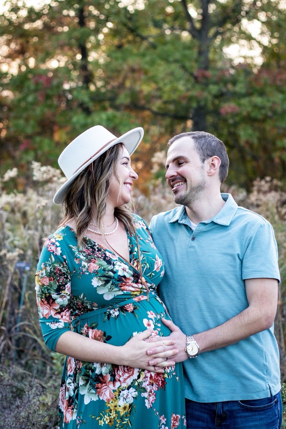 A couple shares a joyful moment outdoors wearing coordinating turquoise and floral outfits in a natural setting. Cincinnati Northern Ky