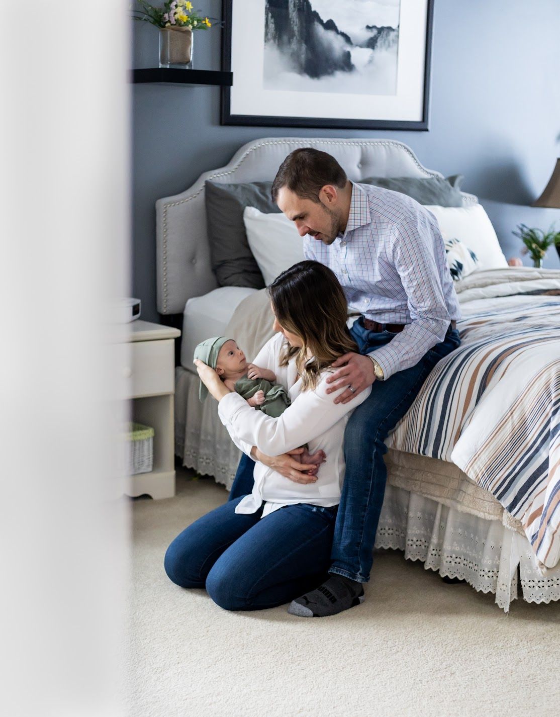 Image showing couple holding their newborn baby on their bed from the hallway.