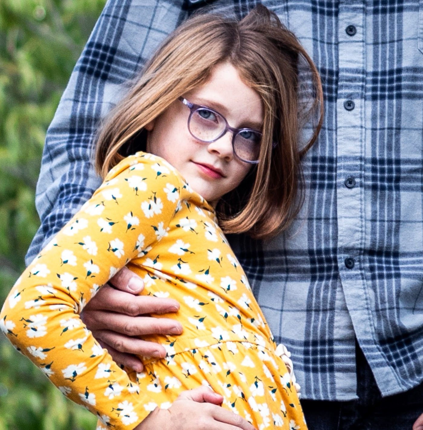 Person in plaid shirt holding a yellow patterned pillow in an outdoor setting. Cincinnati/ Northern Kentucky