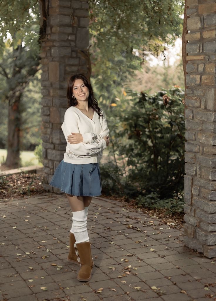 Portrait photo showing female senior in a white sweater and denim shorts against a brick archway. Cincinnati/ northern Kentucky