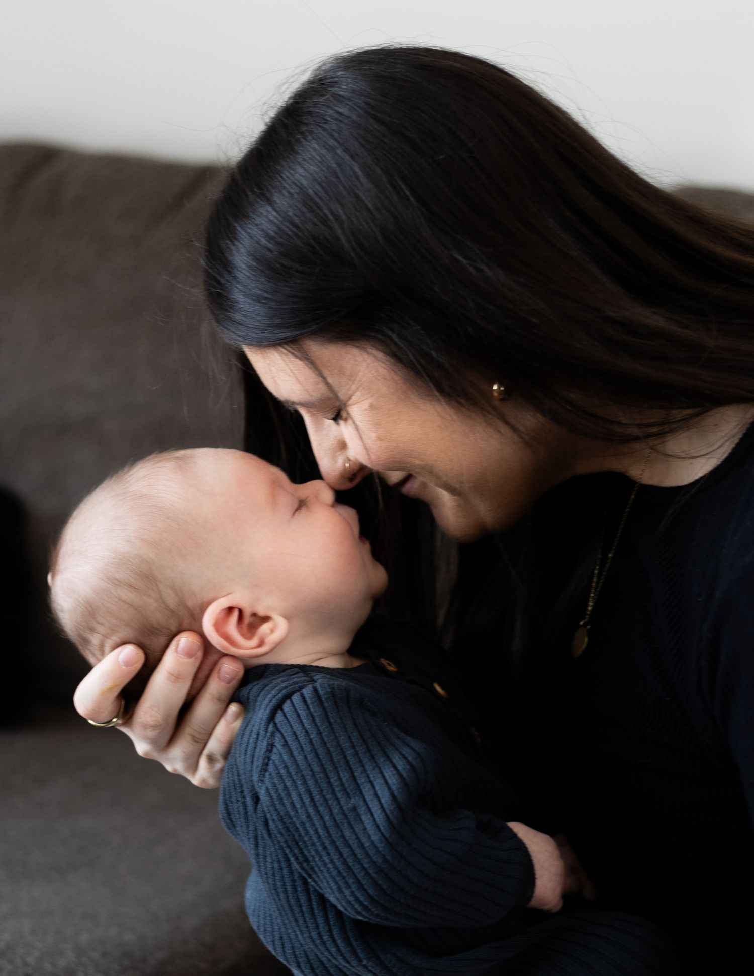 An intimate black and white photosshowing a mother with long dark hair embracing her baby.