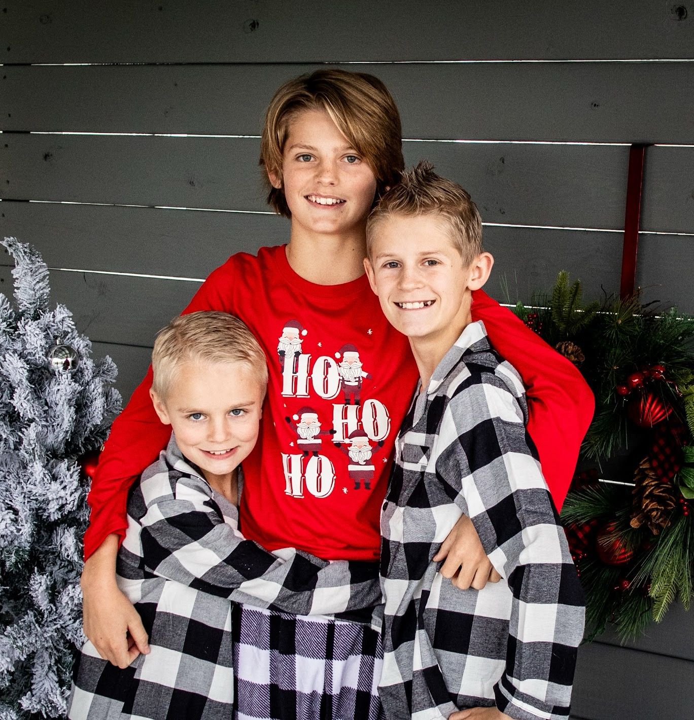 Family members wearing matching buffalo plaid and red holiday outfits pose together for Christmas photos.