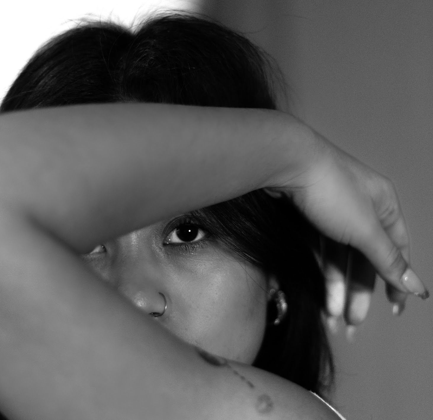 Black and white portrait shot showing a person's face in dramatic lighting and shadow.