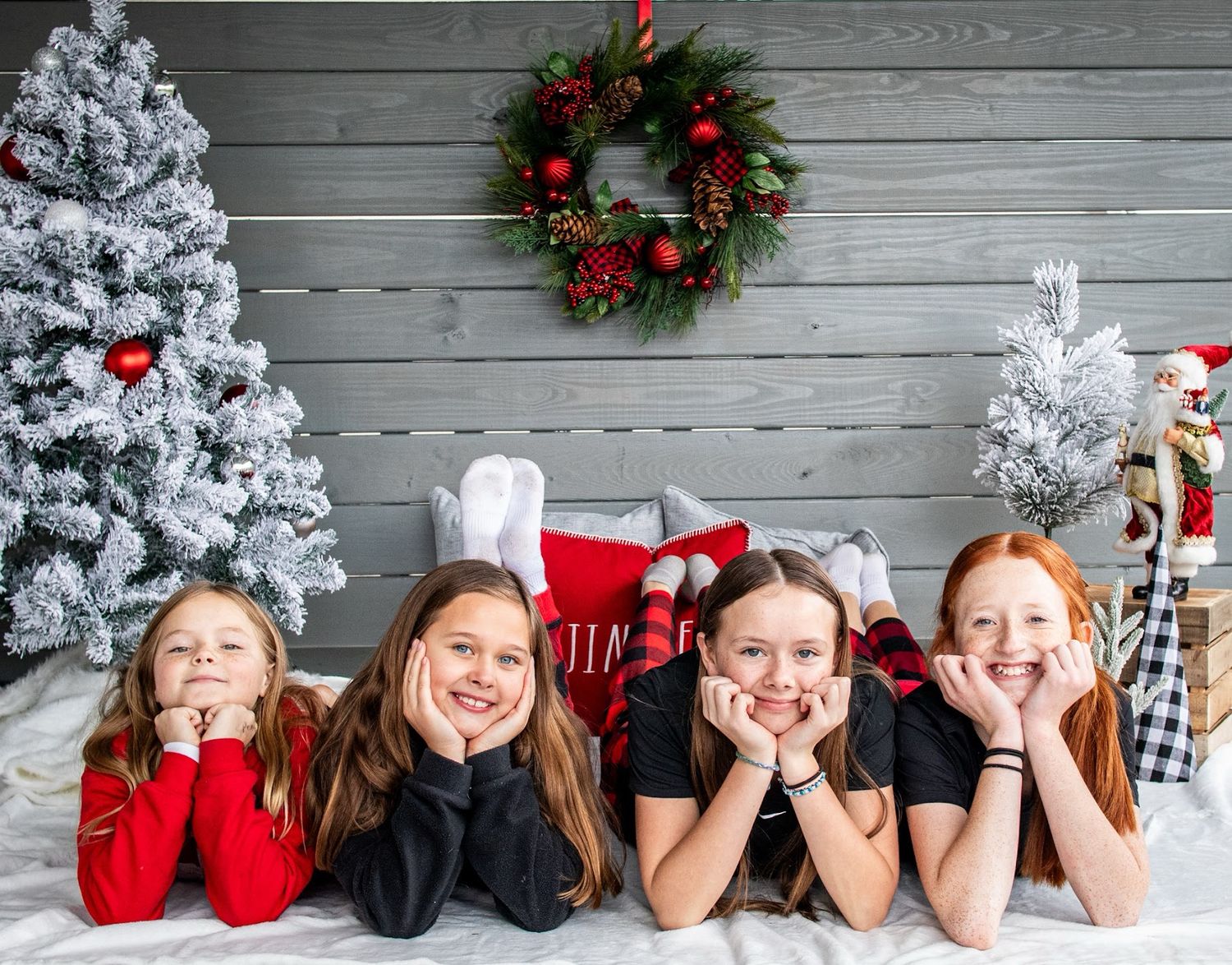 People lying in a row on gray wooden floor with Christmas decorations and snow-covered wreaths against wall. Cincinnati/ northern Kentucky
