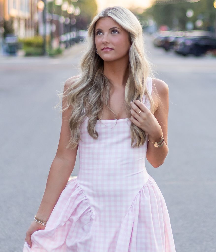 Woman in pink and white gingham summer dress poses in outdoor setting during golden hour. Cincinnati/ northern Kentucky