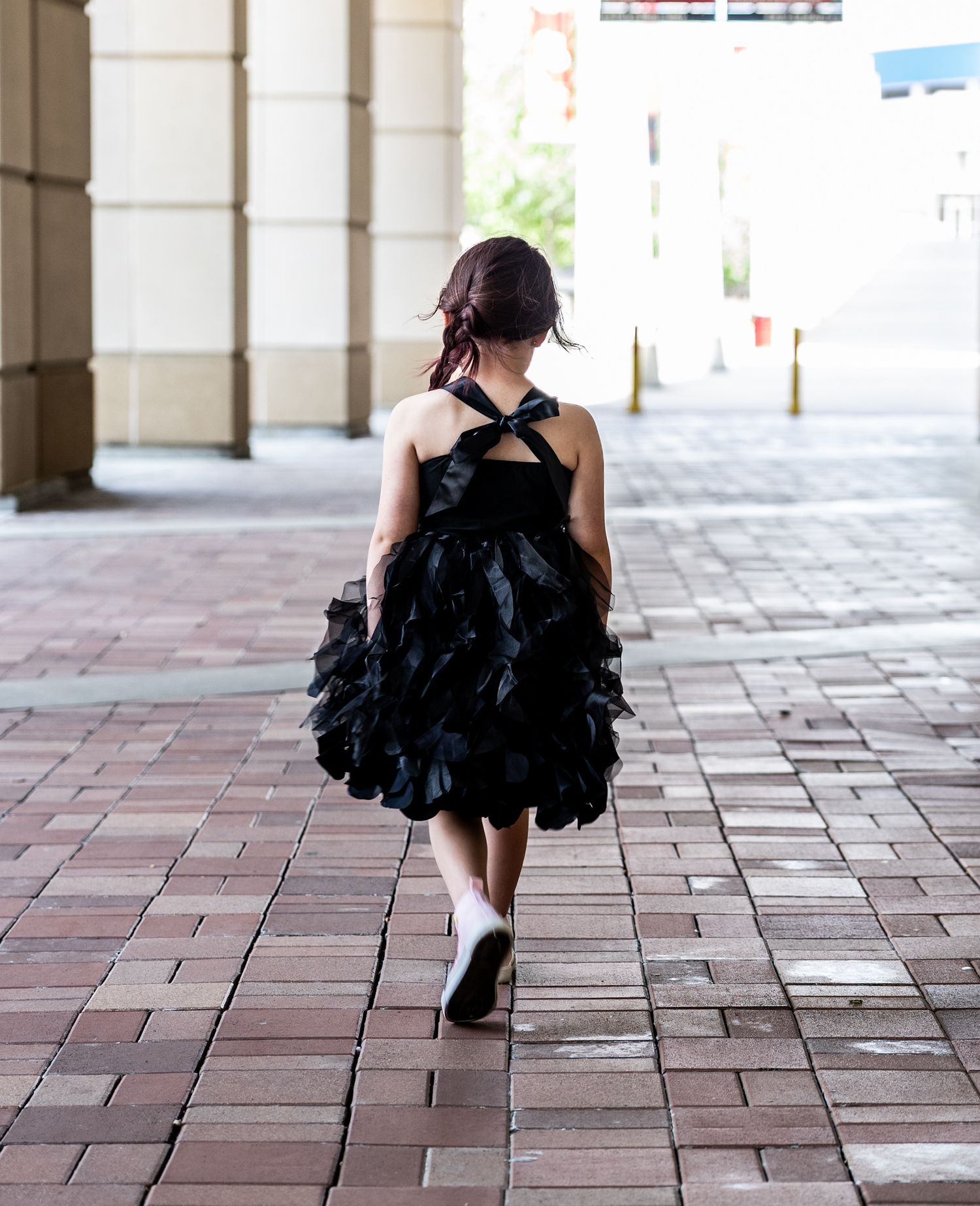 A figure in a black tulle dress walking away from camera