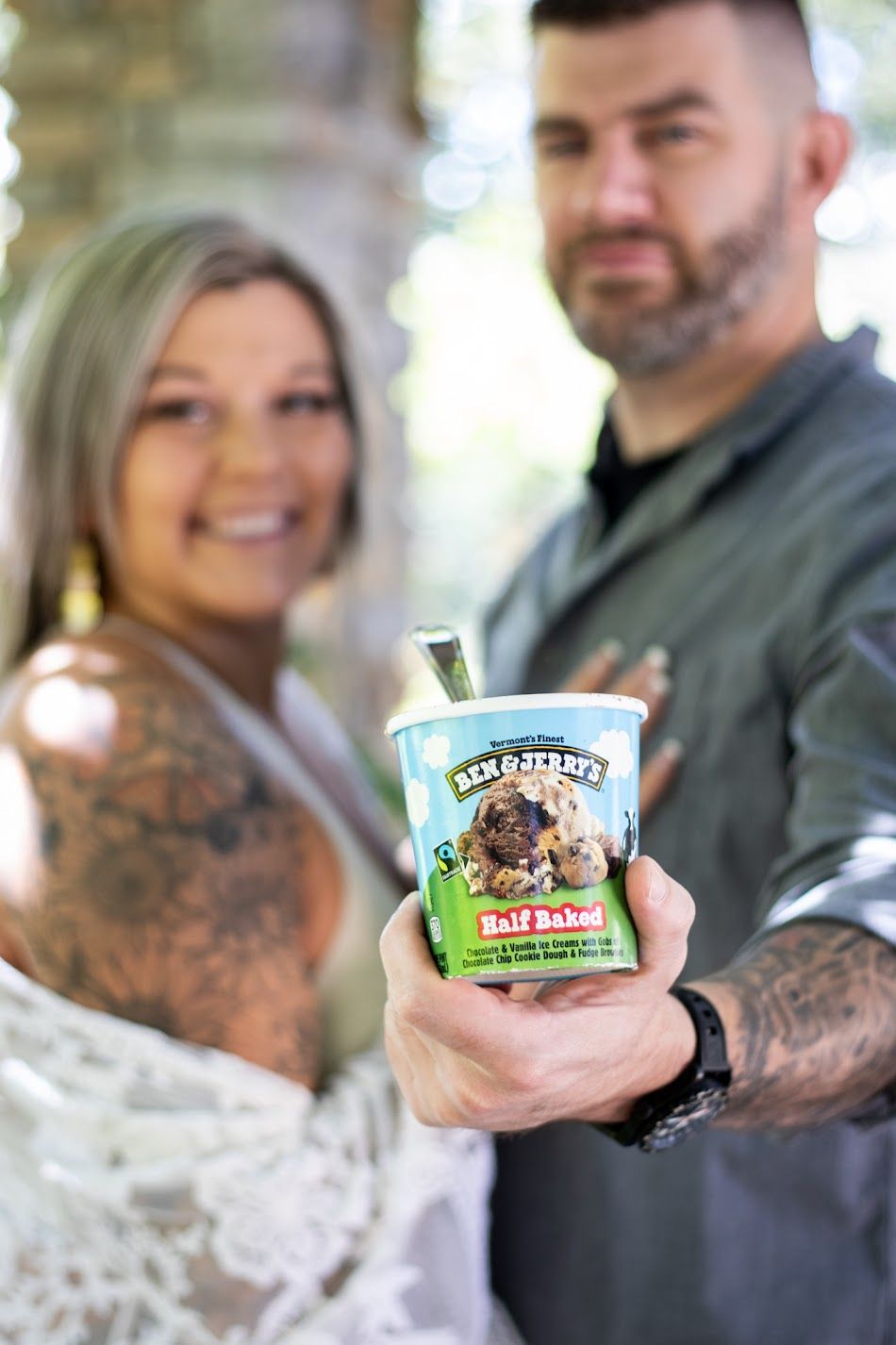 A couple holding Ben & Jerry's ice cream pints together in a half baked themed pregnancy announcement