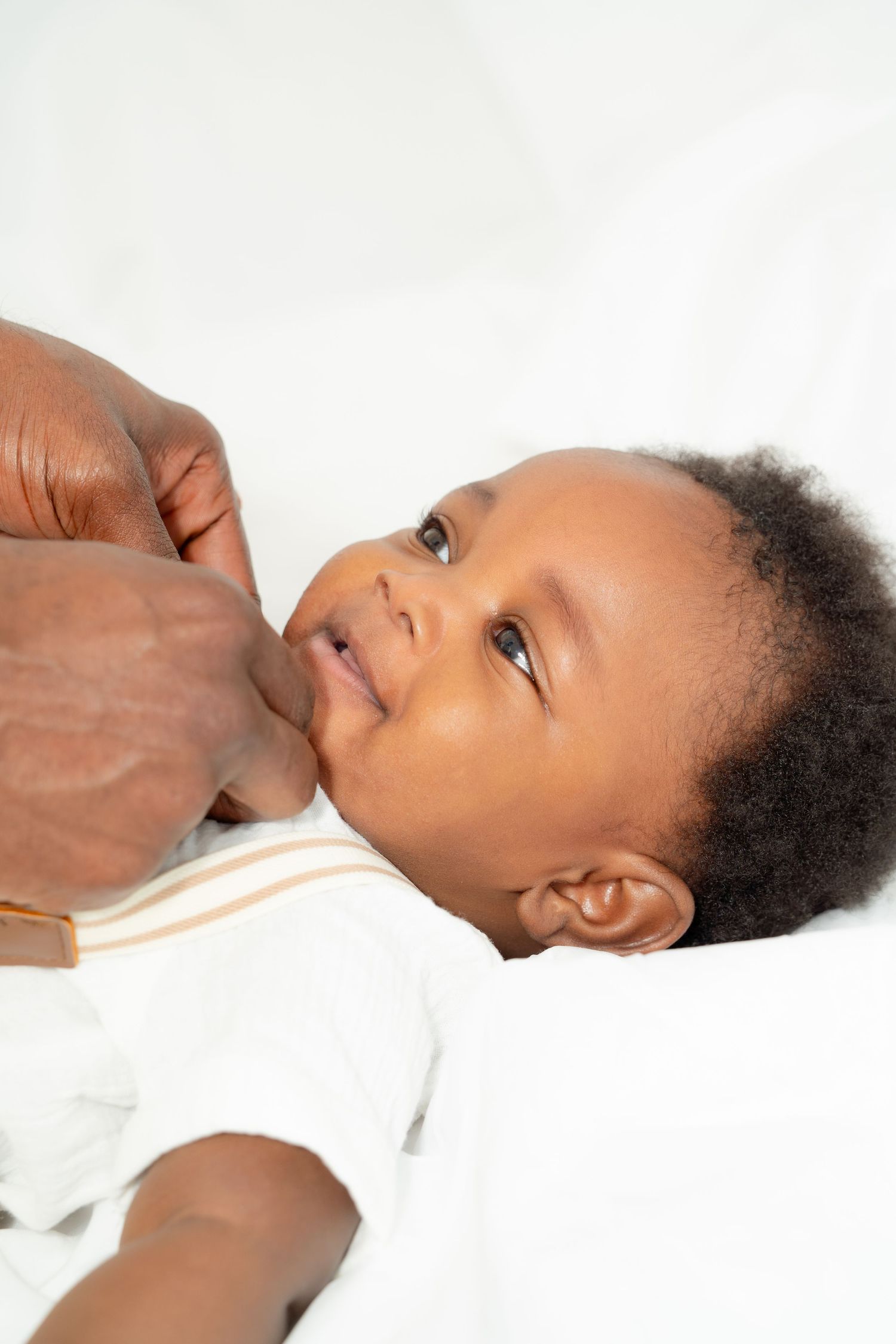 Young child lying down on white fabric while receiving care.
