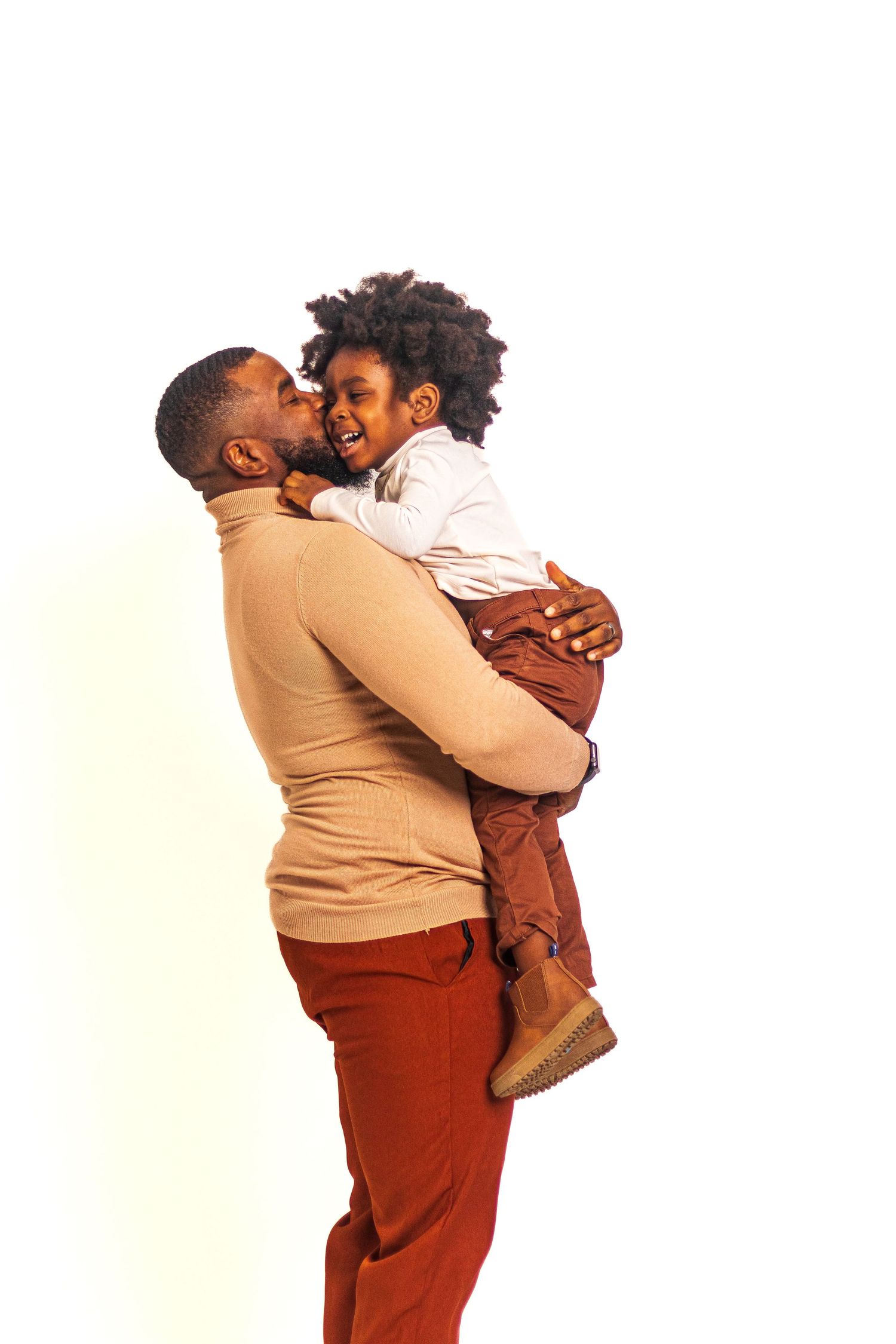 Parent lifting child in playful embrace against white background.