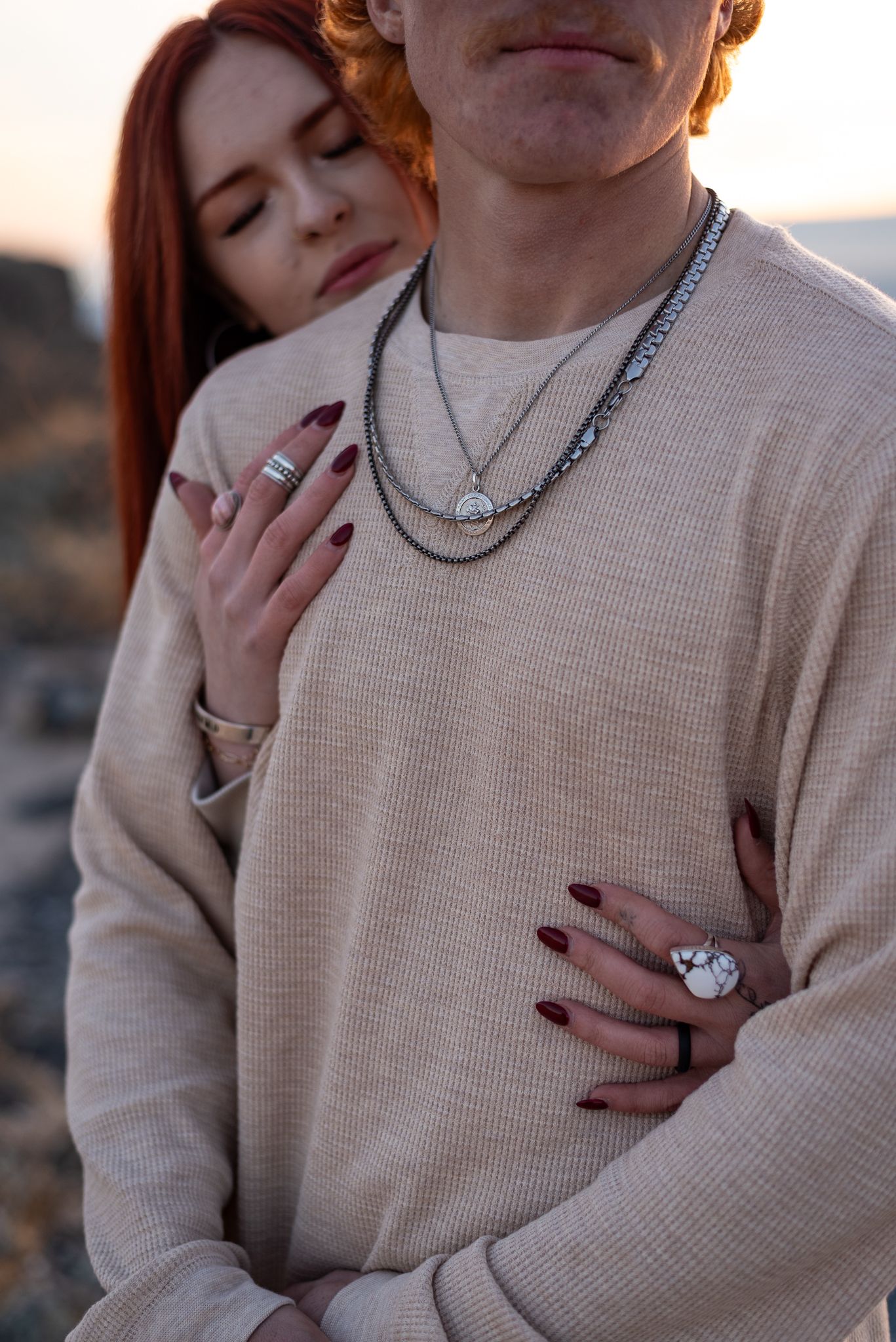 A couple in a cozy cream sweater share an intimate moment during sunset.