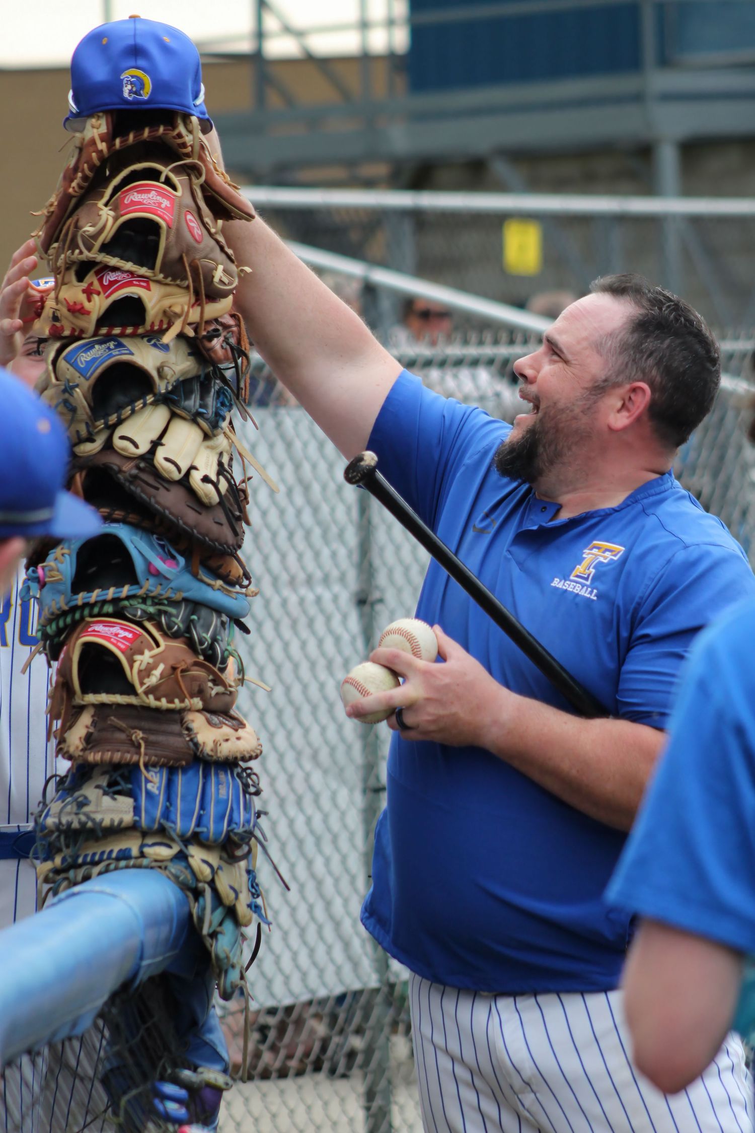 Triton H.S. (Bourbon) Asst. Varsity Baseball Coach stacking his hat on top of his players' stack of baseball gloves waiting out a storm.