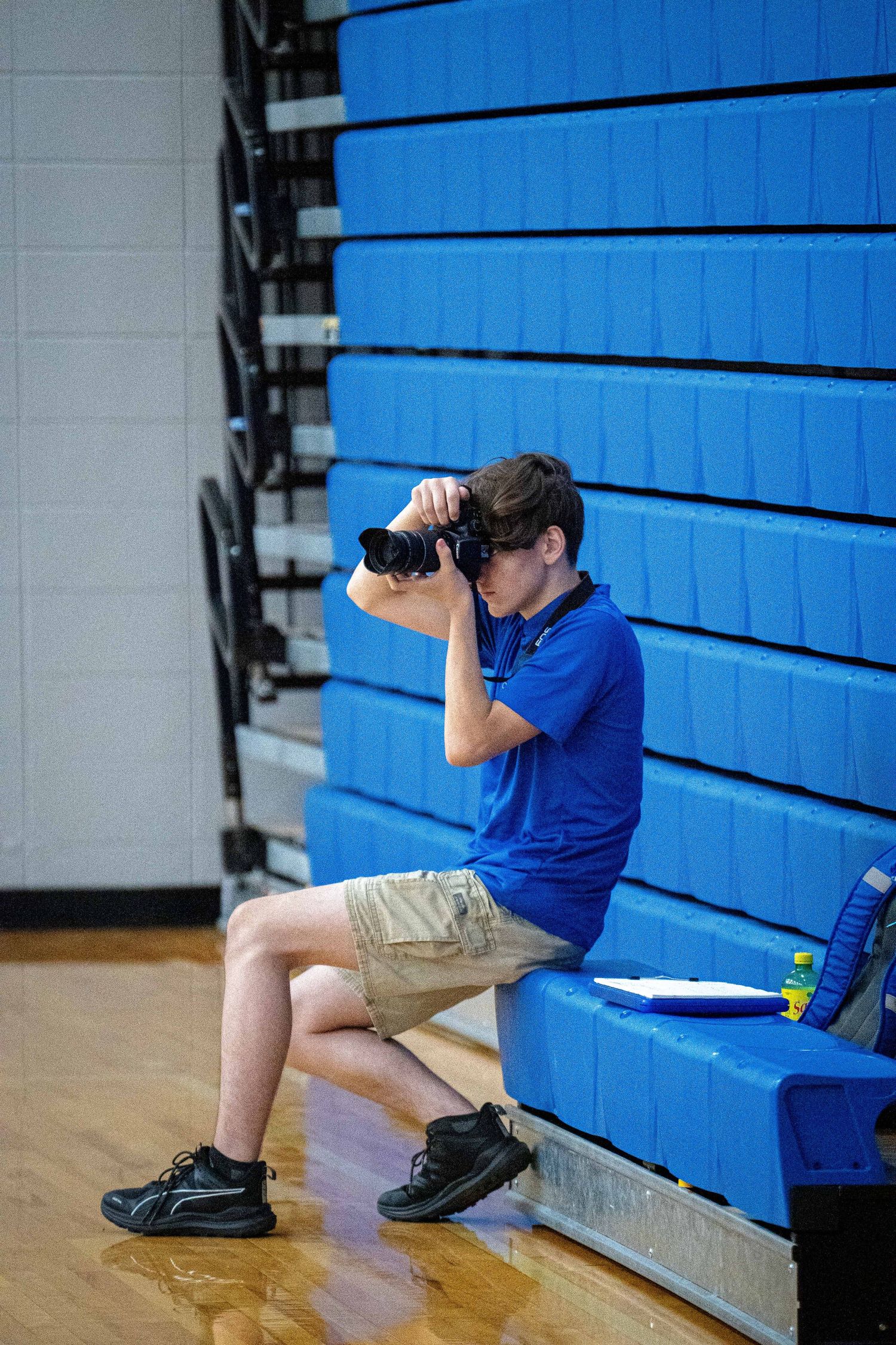 Sylias photographing a volleyball match from the sideline.