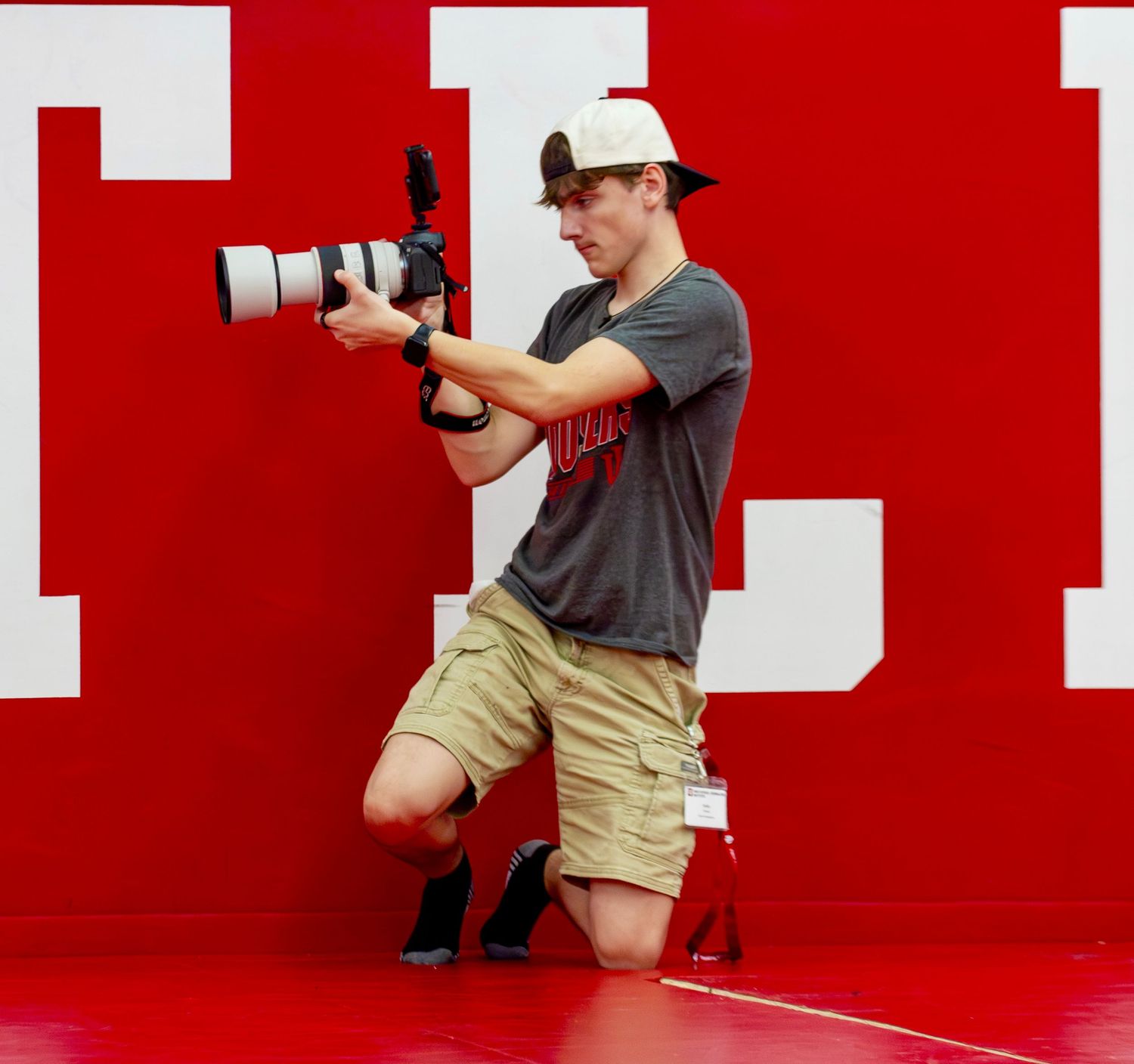 A photograph depicting Sylias Shufelt taking pictures at an Indiana University Wrestling practice in Simon Skjodt Assembly Hall.