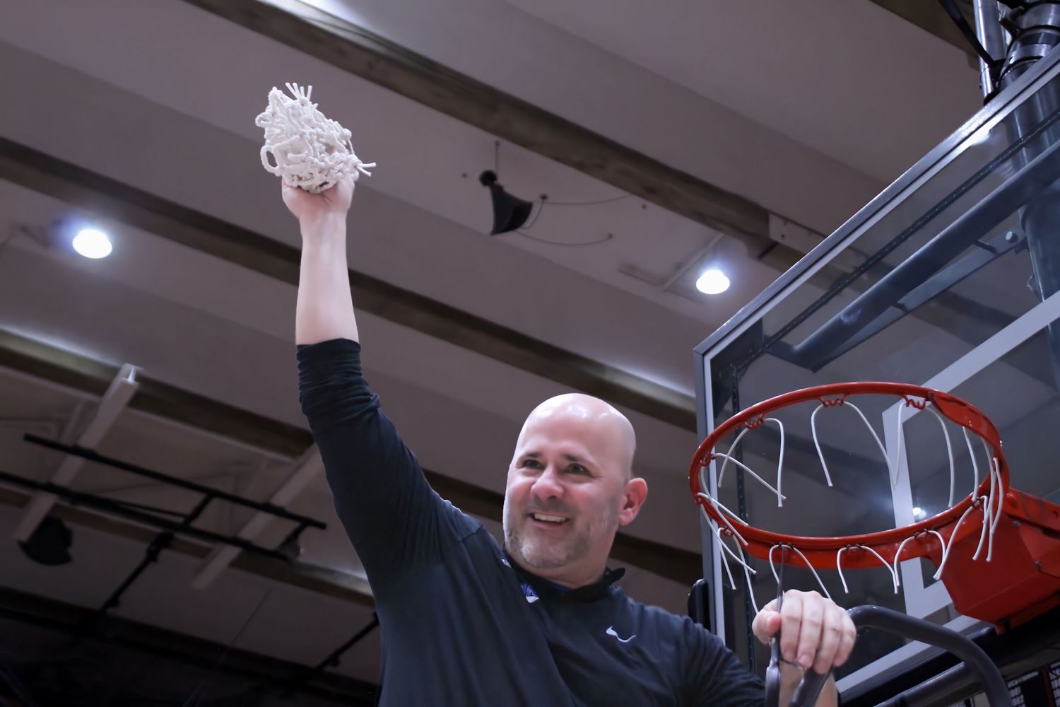 Triton H.S. (Bourbon) Varsity Basketball Head Coach Jason Groves holding the net up in the air after winning the 1A Semi-State championship