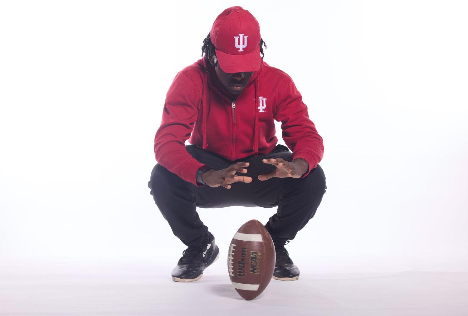 Indiana University HSJI's Khris spinning a football and pretending it's a campfire for a mock studio/media day photograph.