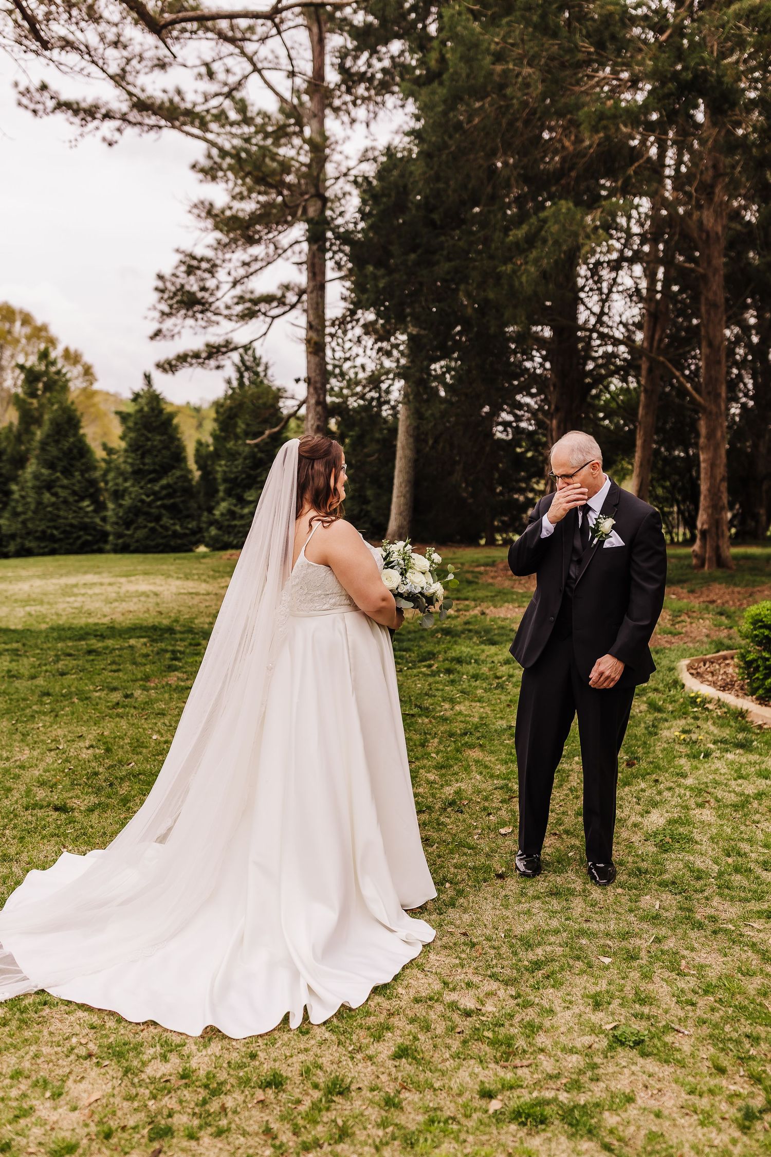 Emotional first look moment between the bride and her father outdoors at Chapman Hill with pine trees in the background.