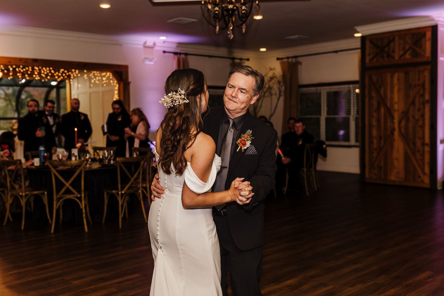 Couples dance together on a dimly lit ballroom floor during an evening reception.