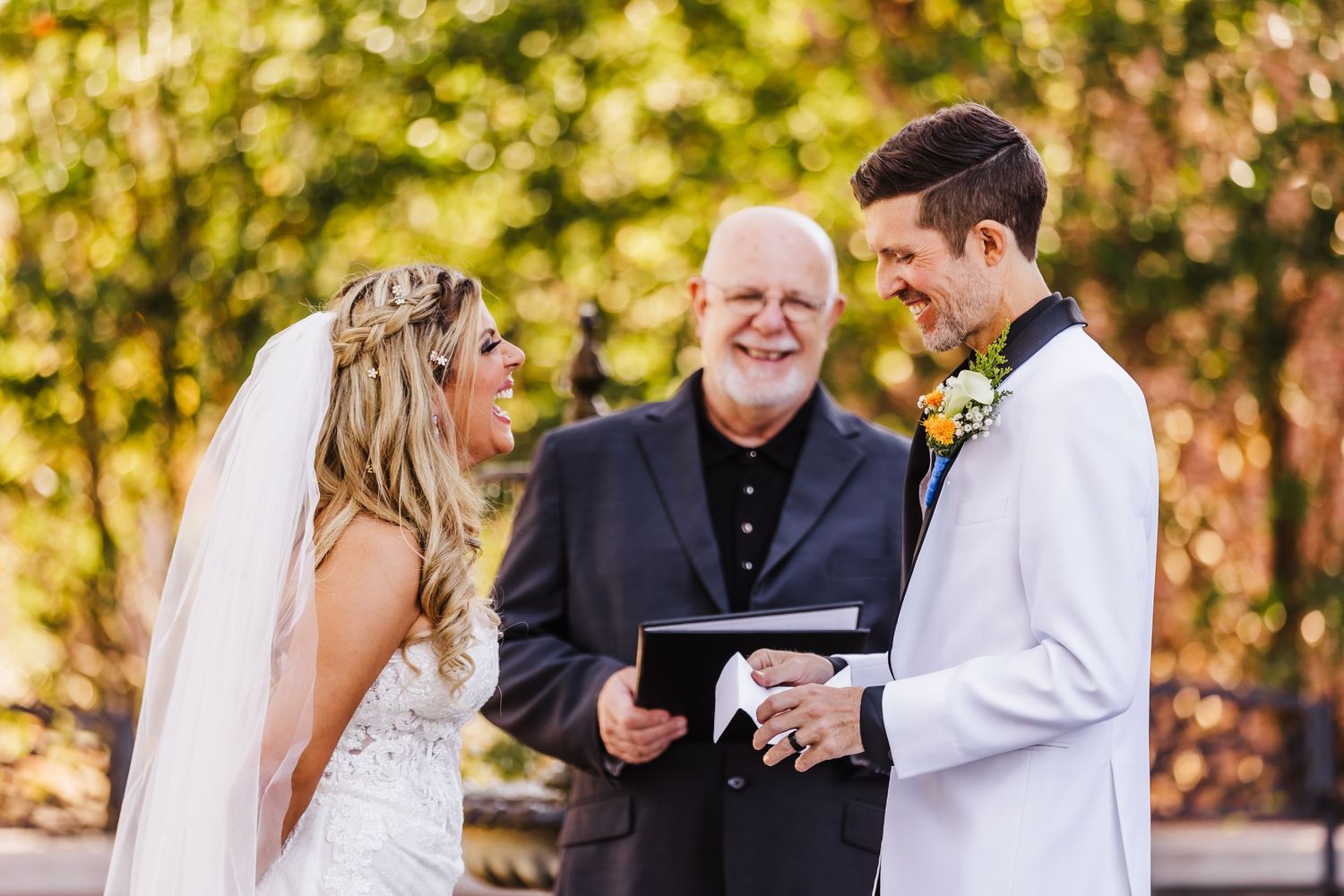 Wedding ceremony in progress with natural sunlit backdrop and floral accents.