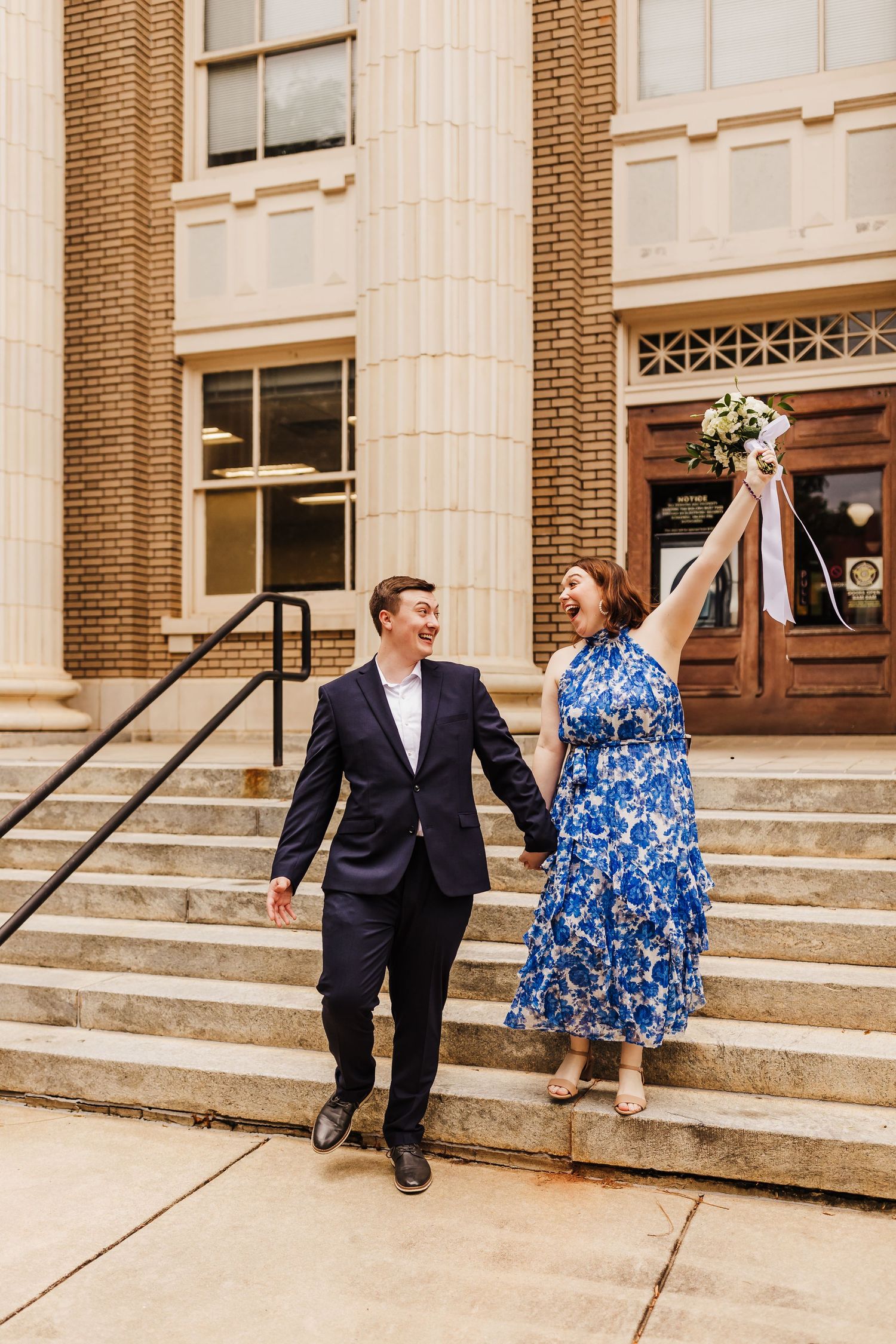 A joyful celebration on the steps of a historic brick building with blue floral dress.