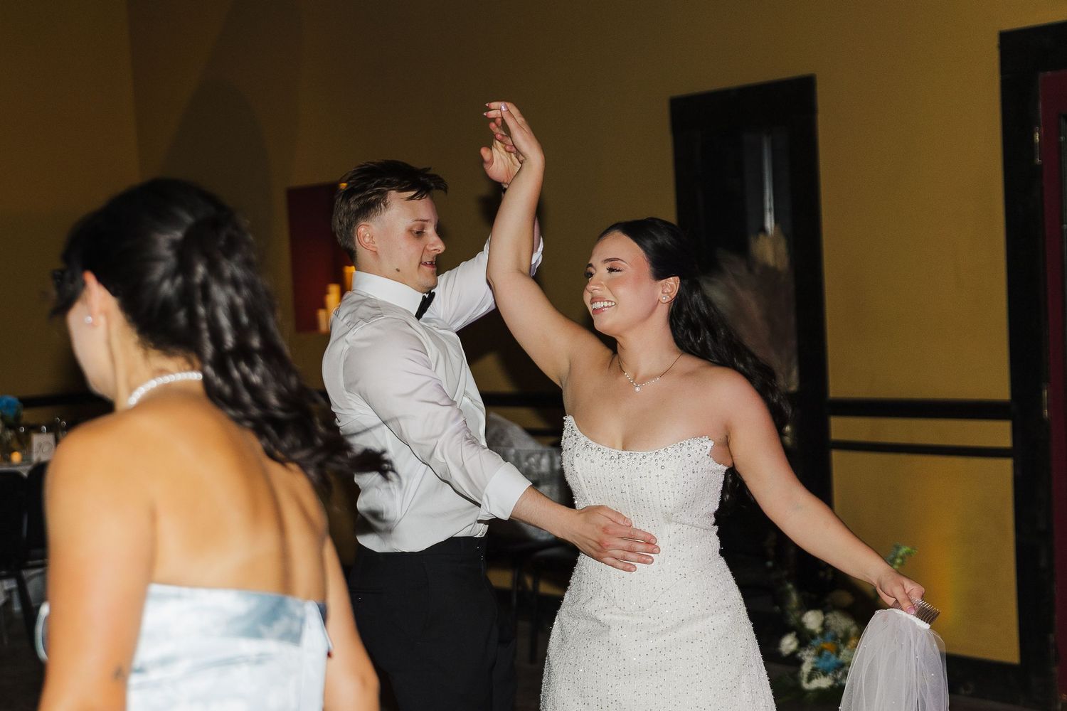 Bride and groom share a joyful first dance at their wedding reception, with the groom spinning his smiling bride.