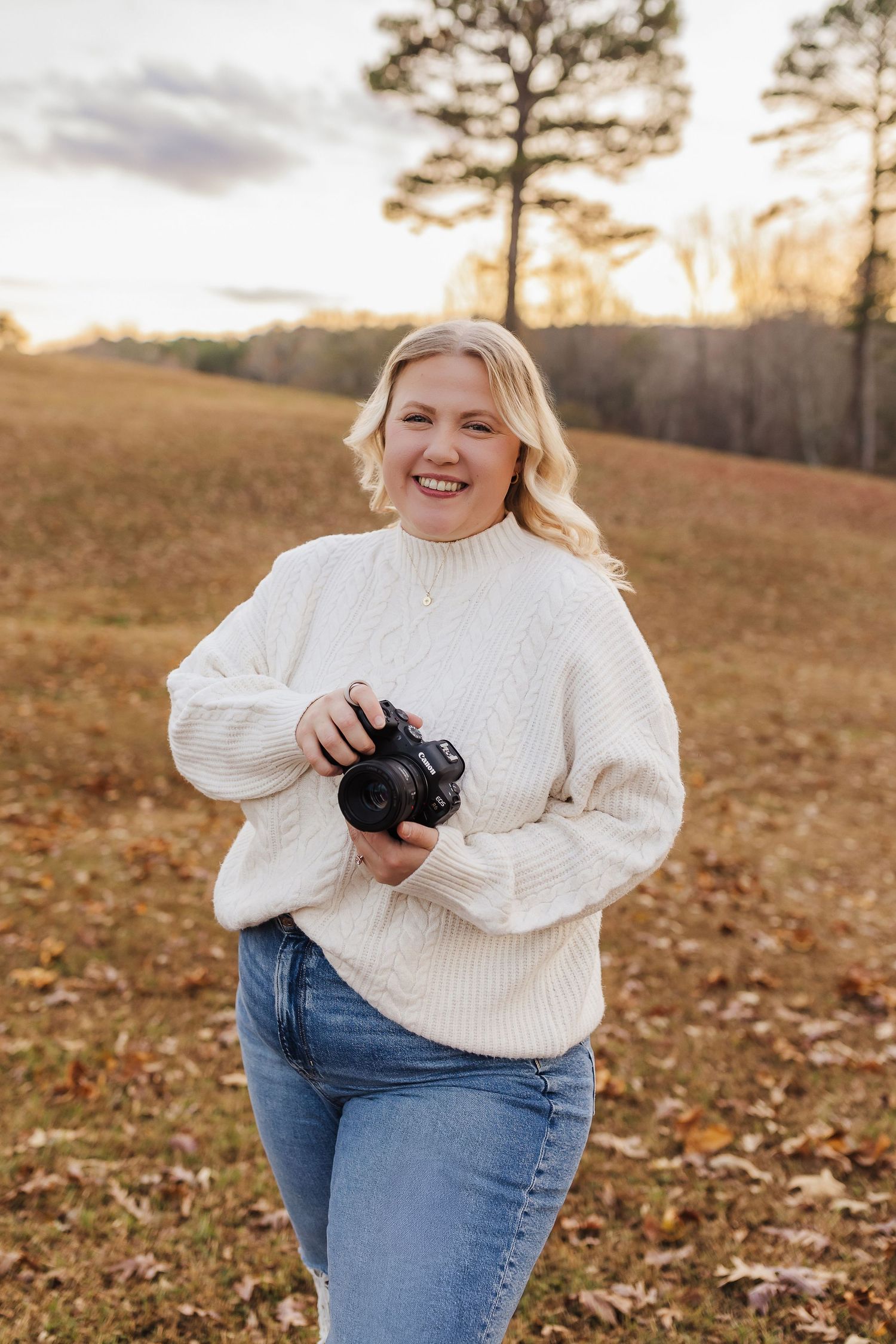 Portrait of photographer holding a camera outdoors during golden hour in North Georgia.