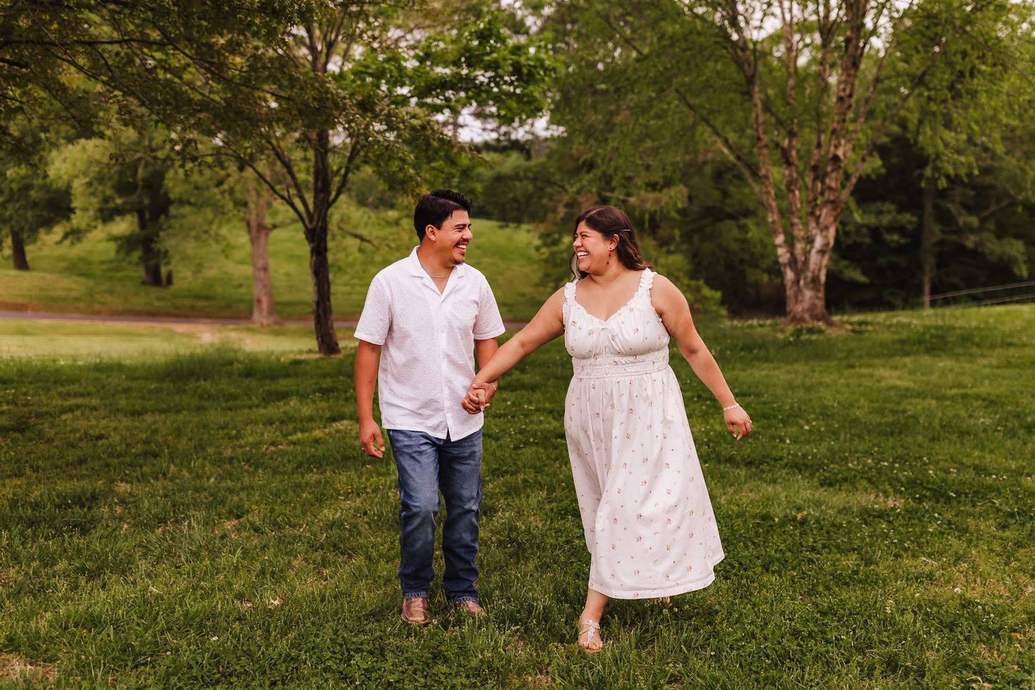 Candid moment of couple walking together in a field during engagement session at Williams Mill Greenspace