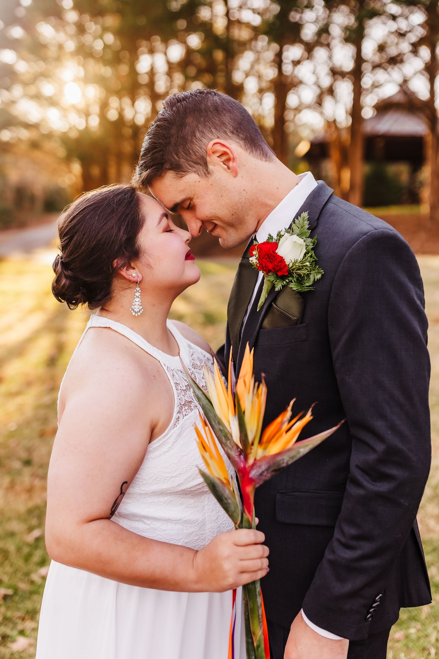 A romantic sunset wedding photo with birds of paradise bouquet and formal attire.