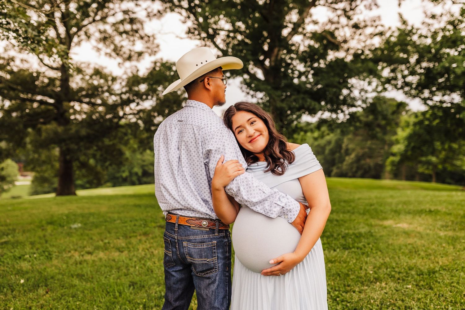 Maternity portrait session with couple in light blue dress and western attire.