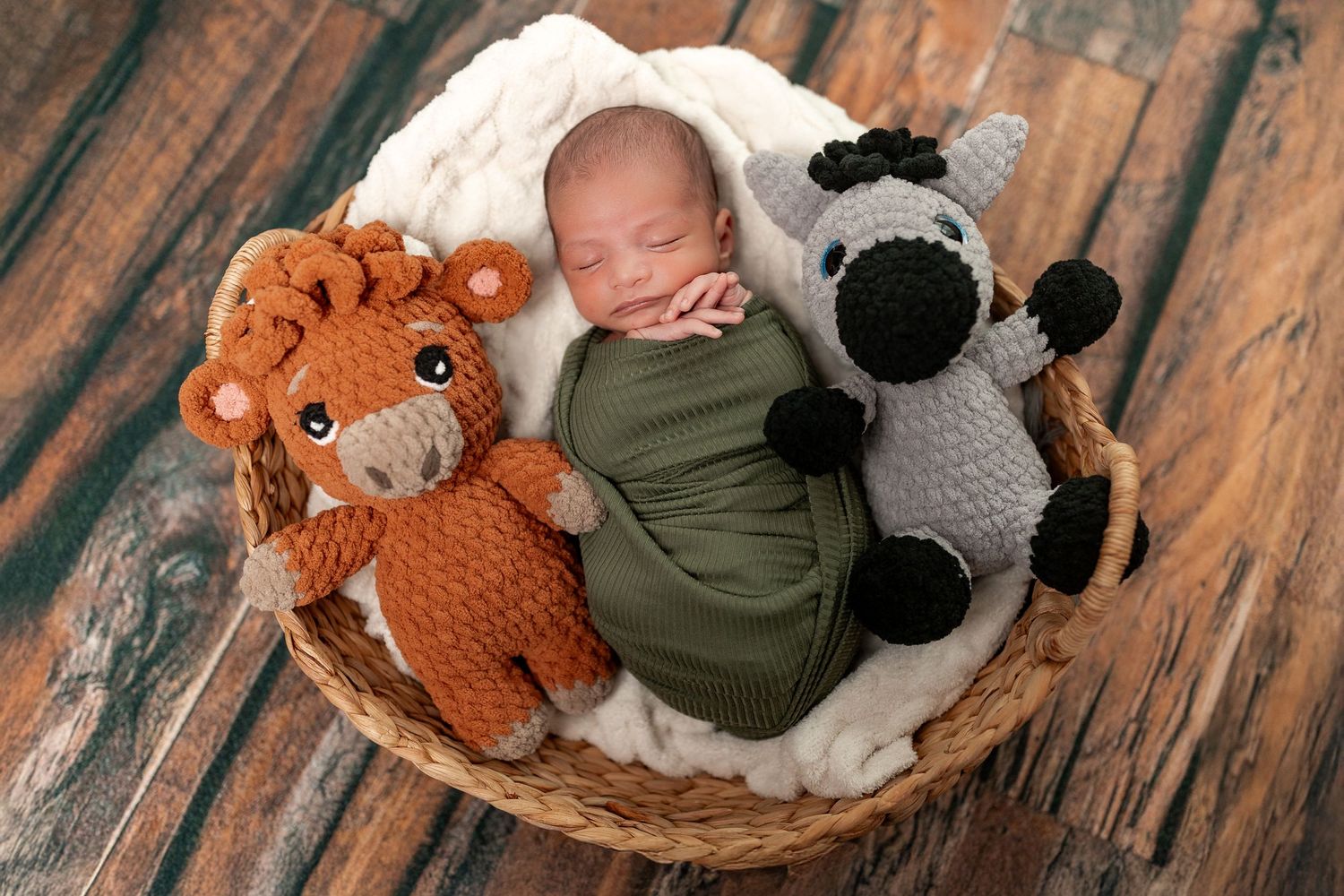 A sleeping baby in a rustic wooden setting with plush animal toys and soft blankets.