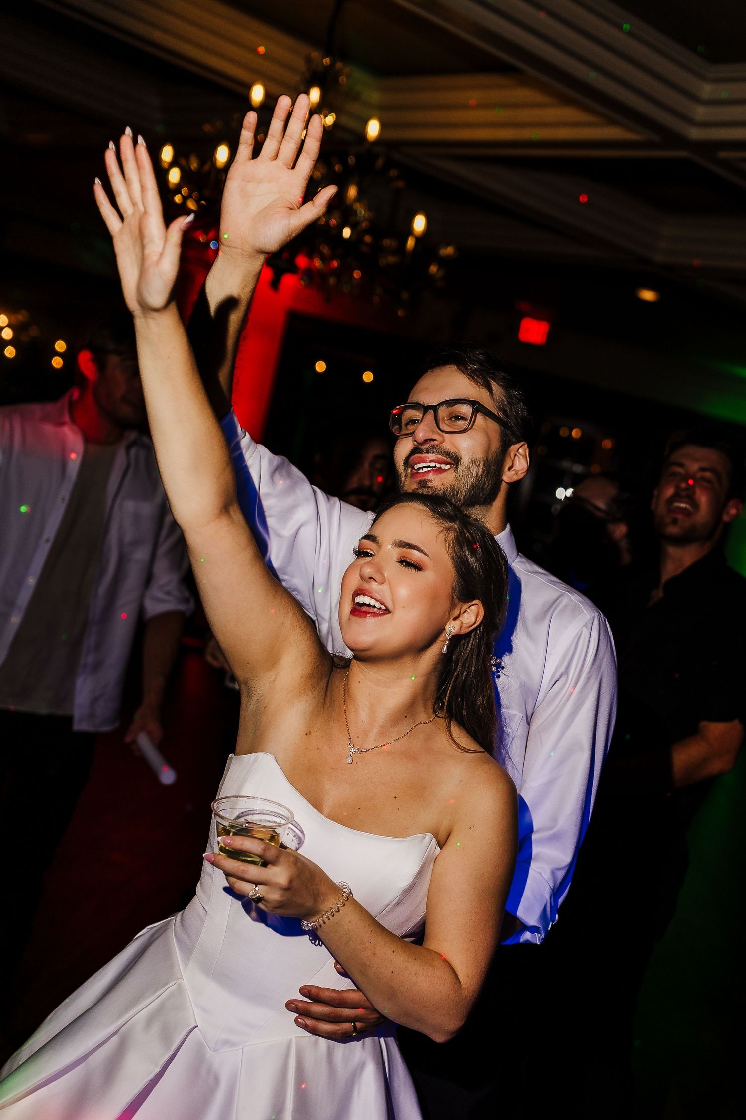 Wedding reception dance party with guests celebrating under dimmed lighting and decorative ceiling.