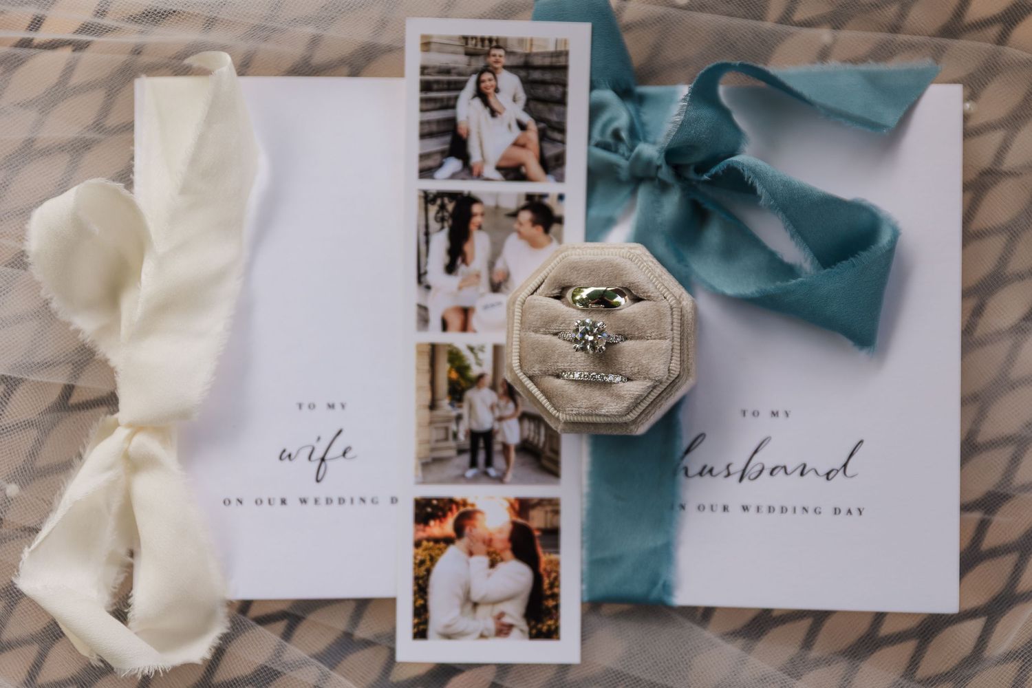Wedding flat lay with engagement ring, couple photo strip, vow books labeled wife and husband, and teal ribbon bow.