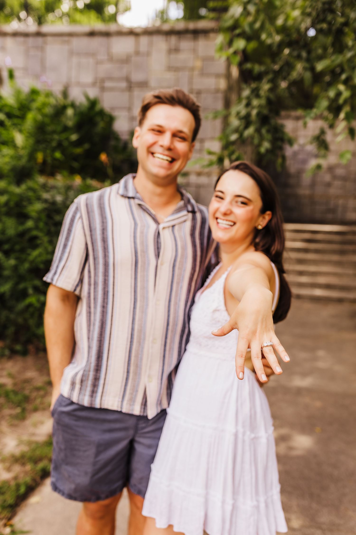 Engaged couple shows off ring in casual outdoor engagement photo session.