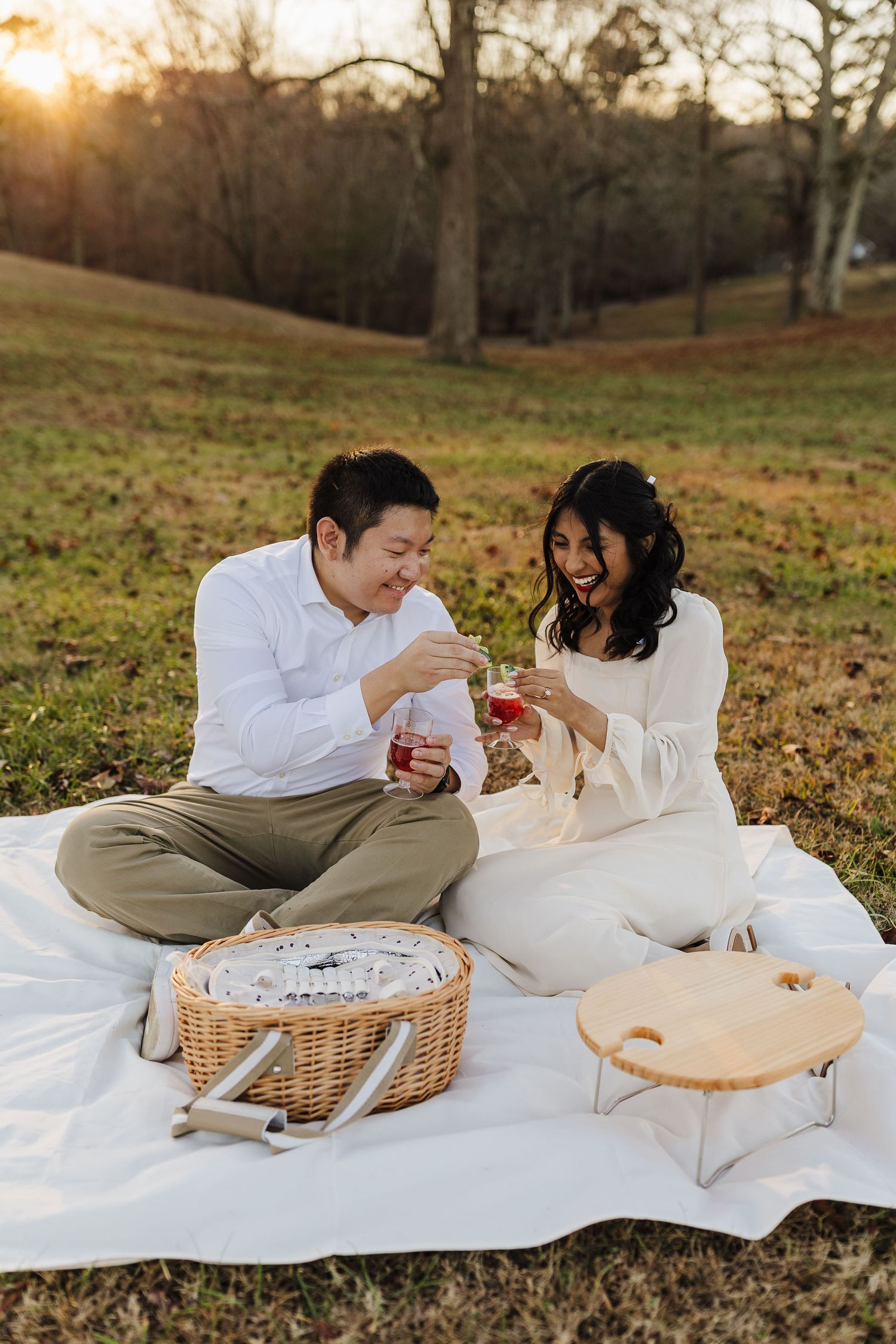Couple enjoying a picnic-style engagement session at Williams Mill Greenspace during golden hour.