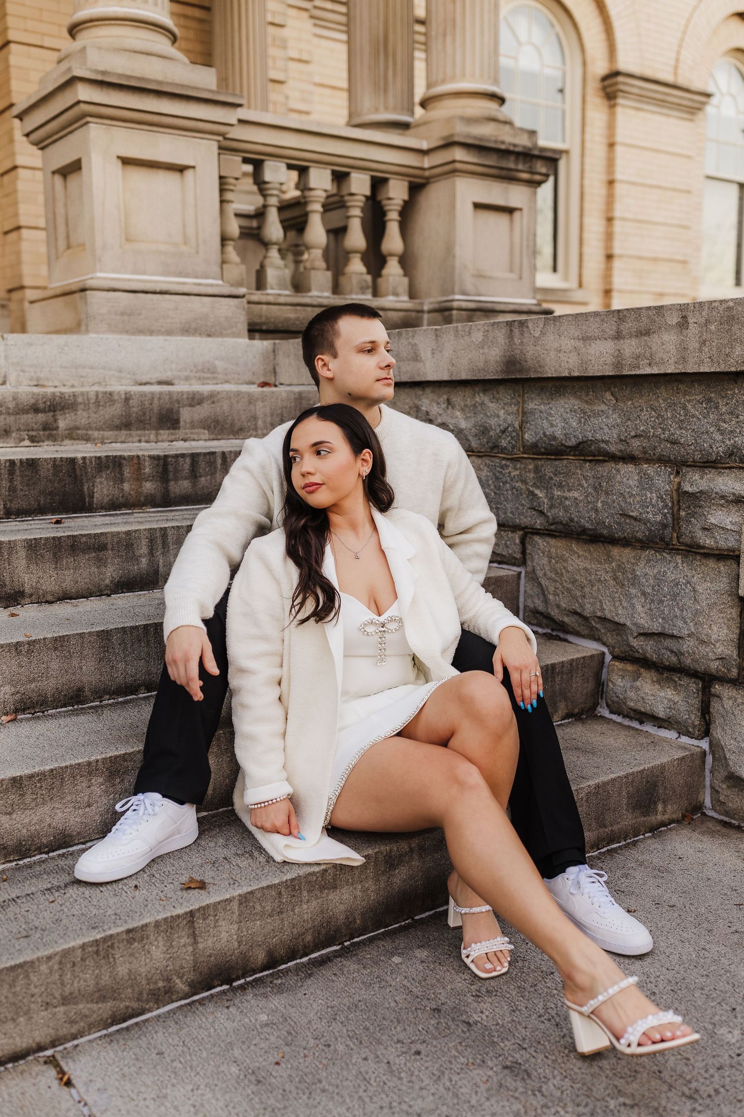 Engaged couple sitting together on the steps during an engagement session at Athens City Hall.