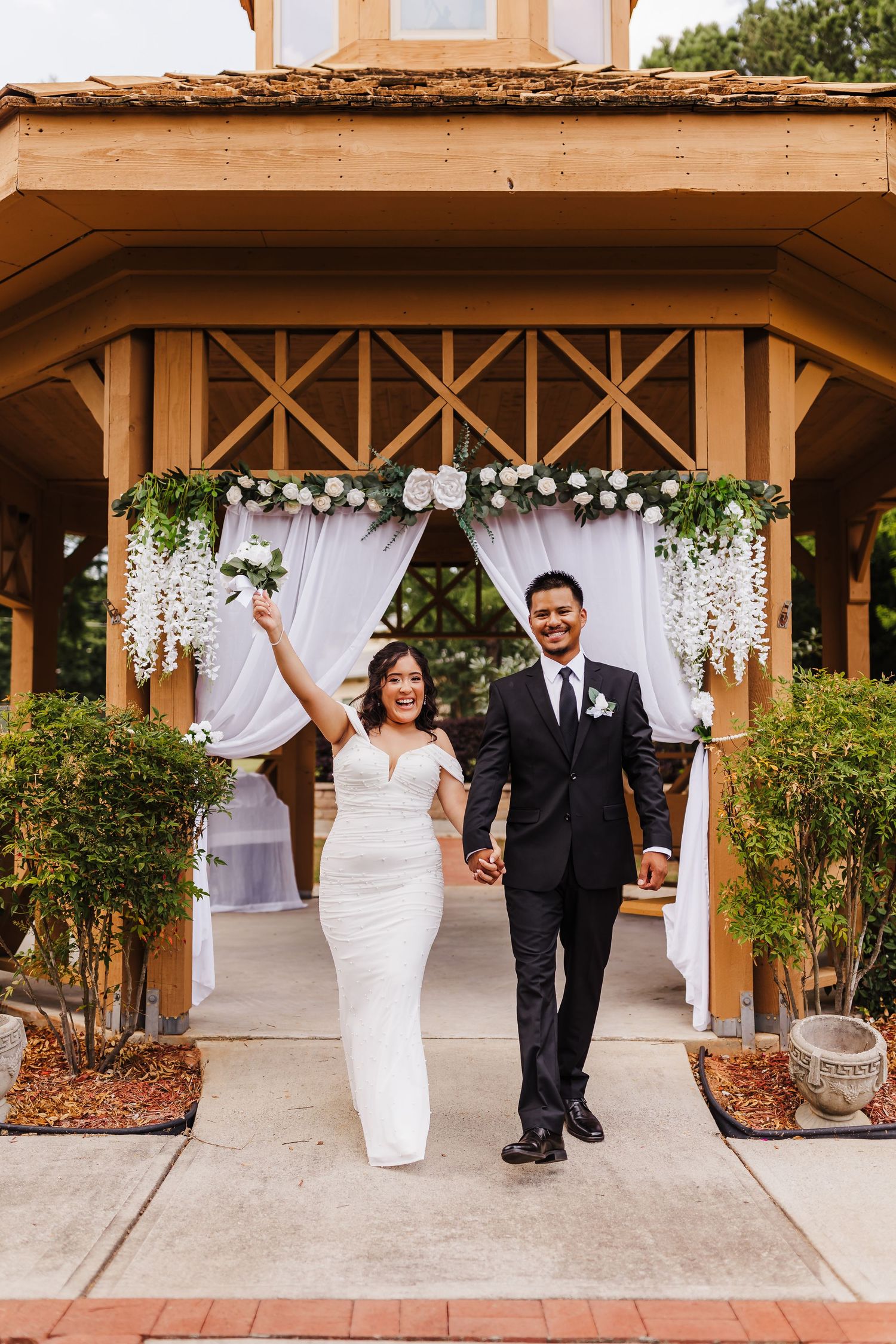 A celebratory exit through a decorated wedding arch with white floral arrangements.