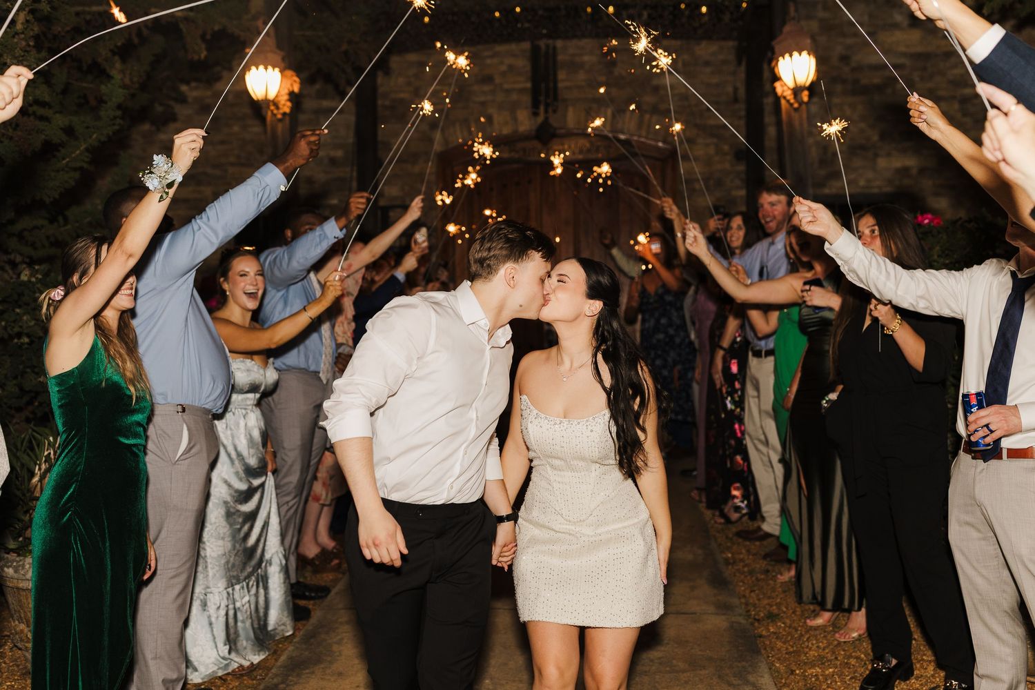 Bride and groom share a kiss during a romantic sparkler exit at their wedding reception.